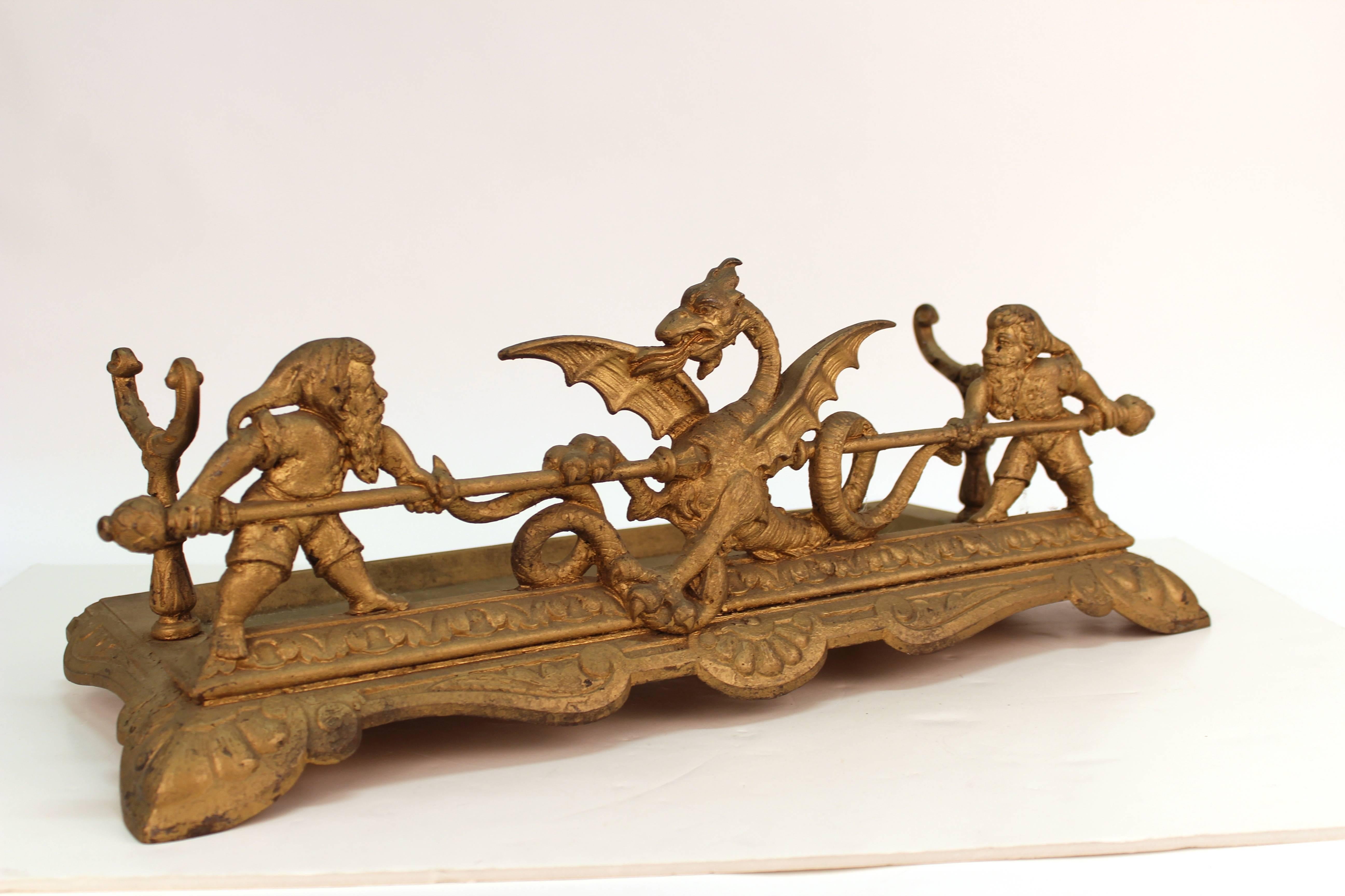 An American Victorian iron fireplace tool cradle with gnome and dragon details. In gold gilt finish. Made in the 1880s-1890s in the United States. In great vintage condition.