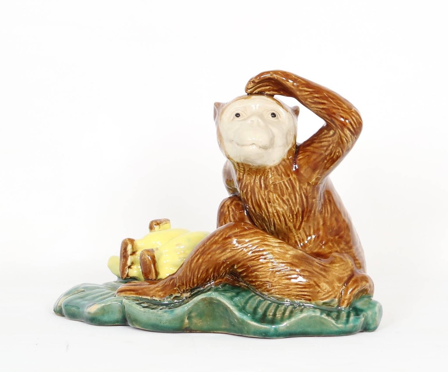 Early 20th century English majolica monkey figurine features a monkey peering into the distance next to a pile of bananas. This figurine is in excellent vintage condition and has wear consistent with age and use. 