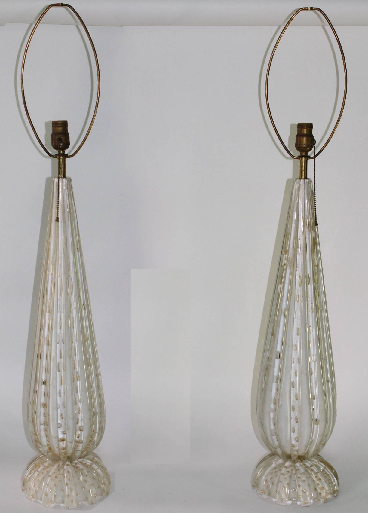 Murano glass table lamps with a pattern of gold flakes. Features tall glass bodies with scalloped base. Wear appropriate to age and use. The pair are in good vintage condition.

The glass bodies of the lamps measure 27.75