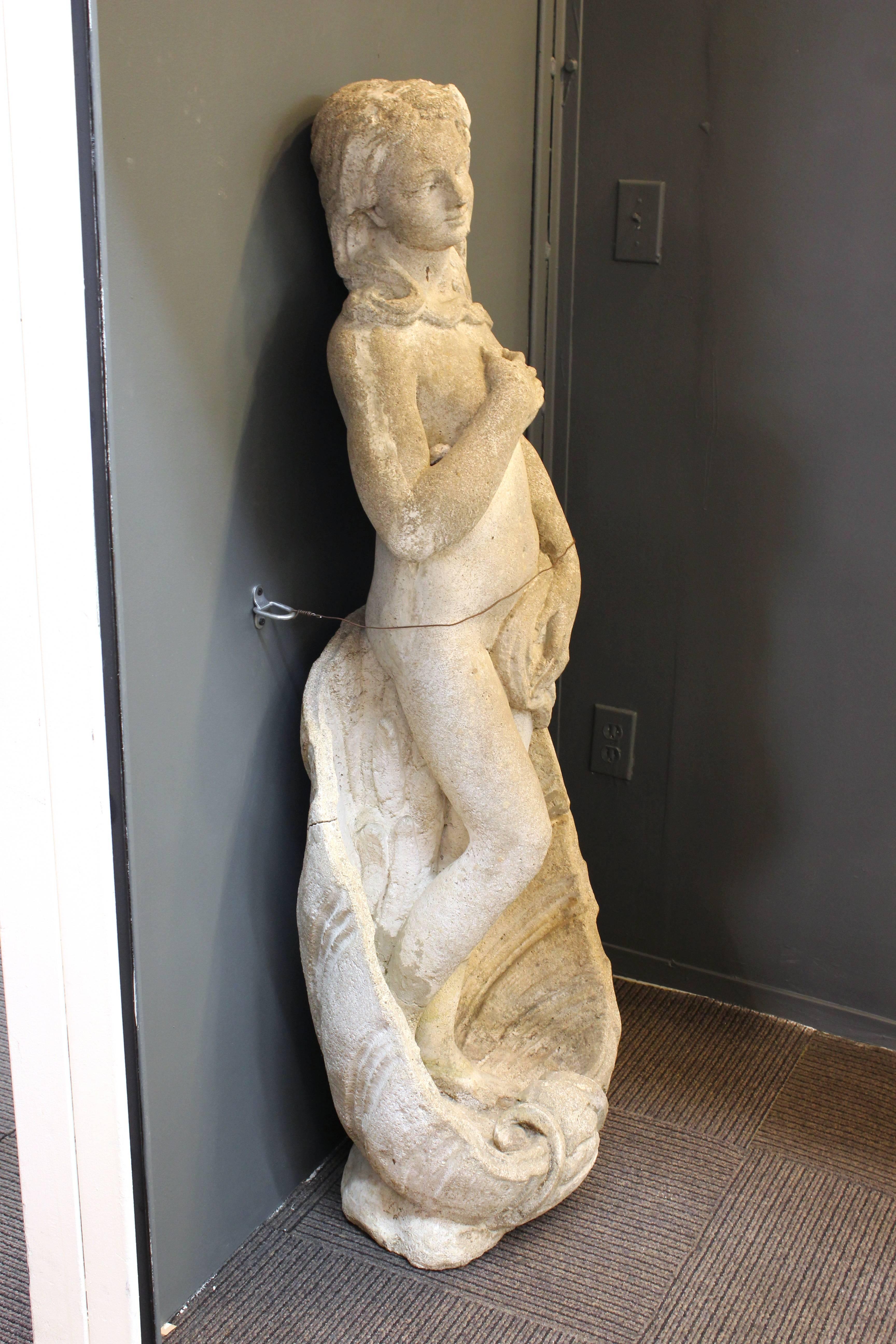 An outdoor garden statue made of cement stone, depicting Venus in a pose similar to the famed Botticelli painting 'Birth of Venus'. The piece is in good vintage condition.