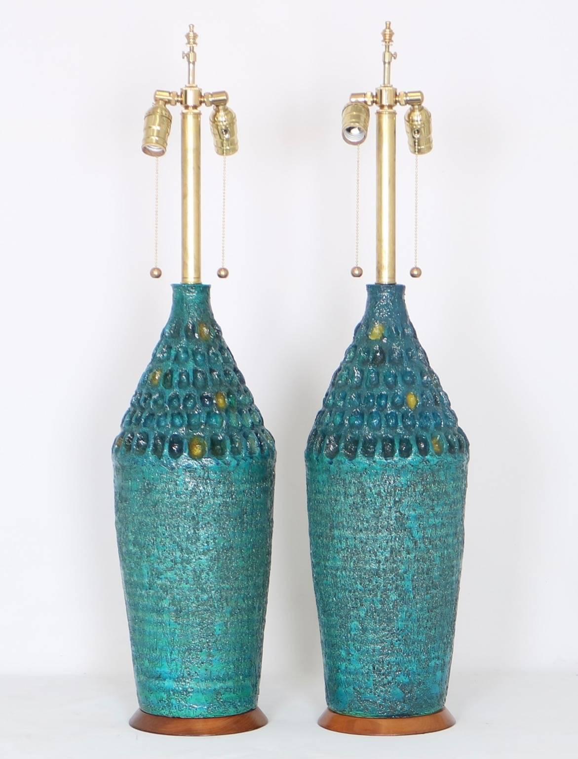 Brutalist style table lamps produced by Quartite Creative Corp. These lamps are dated 1965 and feature textured ceramic turquoise bodies glazed in variants of blues, greens and yellows. The noted height is to the finial each lamp is fully restored