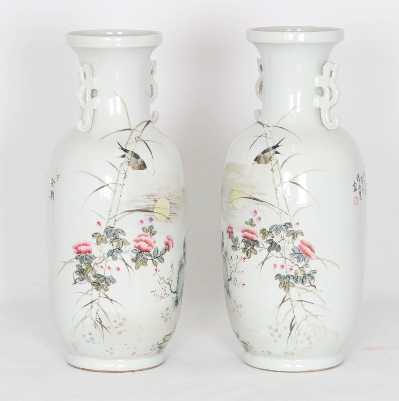 Chinese vases with enamel illustrations. Features miniature landscapes with birds, flowers and calligraphy against a glossy white background. Includes small decorative handles on each. Wear appropriate to age and use. The pair are in excellent