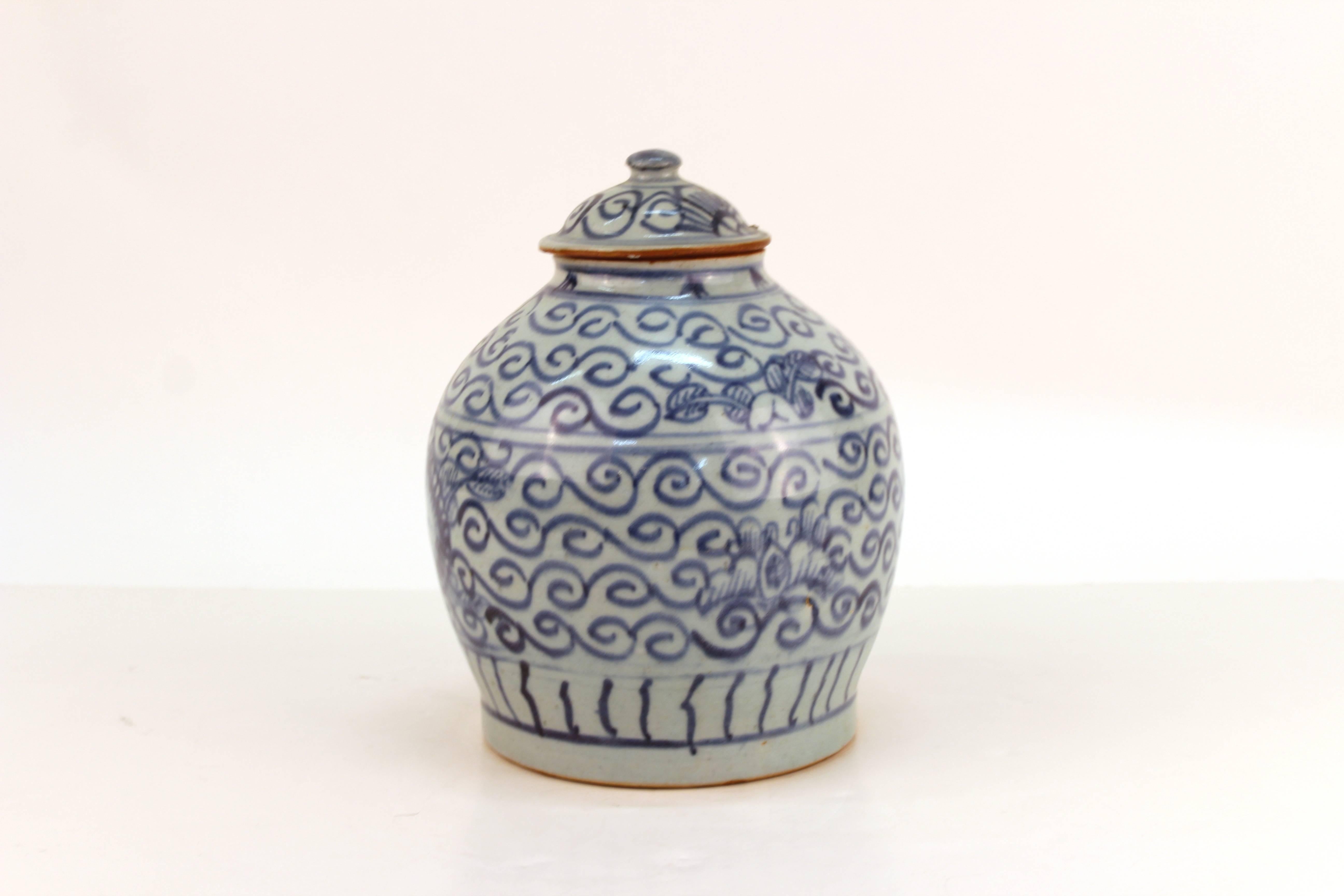 Chinese produced jar crafted for the Persian market. White glazed ceramic with swirling patterns and floral decoration in blue. Includes a matching lid. Some dimples or small spots in glaze due to production process. Wear appropriate to age and use.