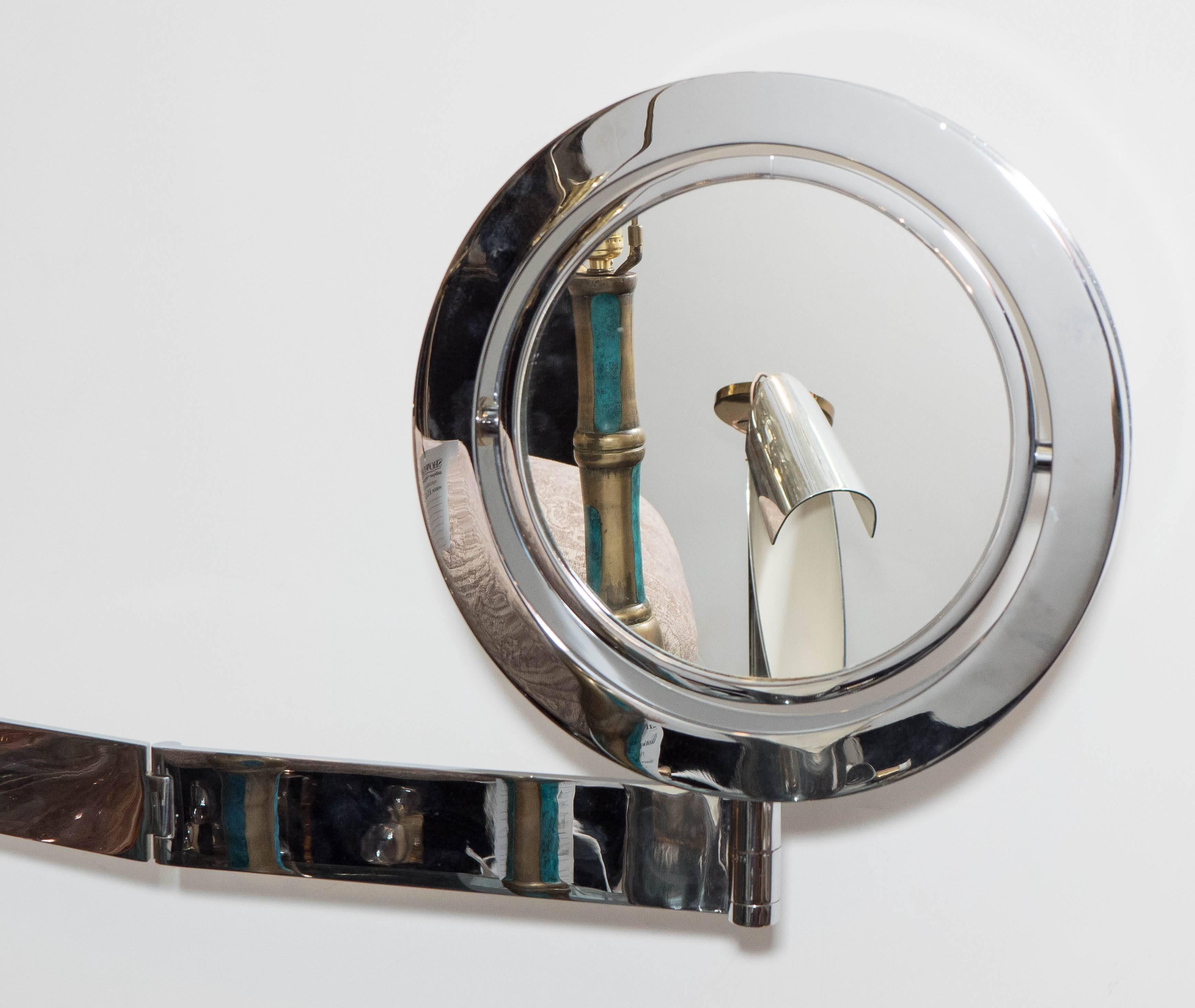 A chrome wall-mounted 'Saturn mirror,' intended for shaving or makeup application, featuring an adjustable arm, with a pivoting mirror that magnifies on one side. Good condition, wear to the chrome consistent with age and use, with minor scuffs to