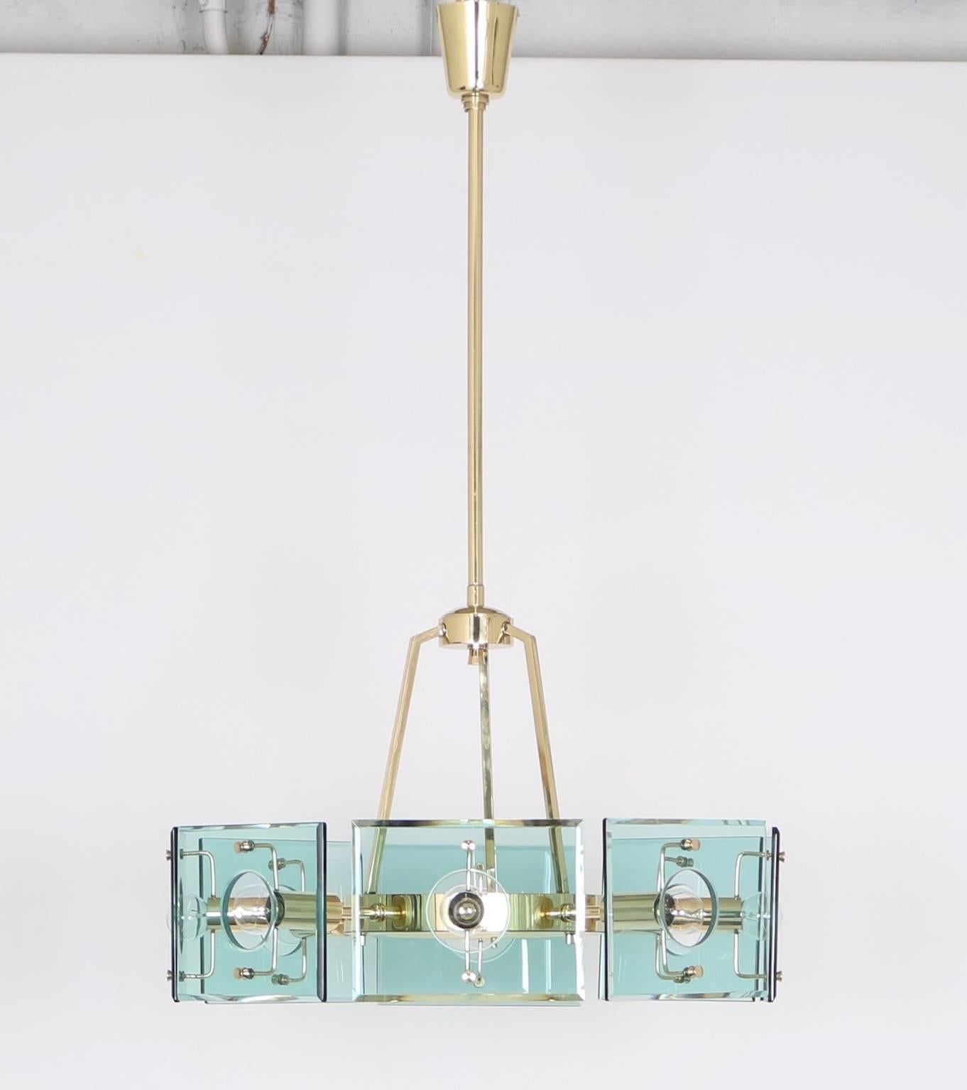 Italian chandelier designed by Gino Paroldo for Fontana Arte, circa 1950s, brass frame with cut-glass geometric panels. Completely restored and adapted to US standard, requires candelabra bulbs.

 