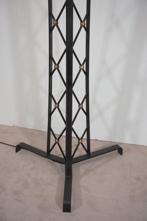 A pair of large-scale, floor lamps, following the style of Jean Royère's signature 'Tour Eiffel' designs, in black painted wrought iron, with three panels of lattice brackets (otherwise 'croisillons'), with intersecting brass-plated accent balls,