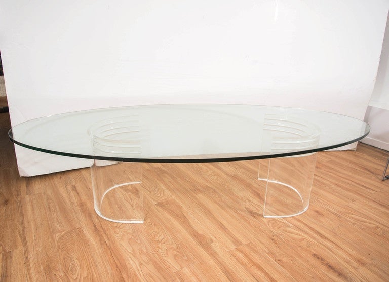 A vintage coffee and cocktail table, produced circa 1970s, with large oval form glass top on two thick 'C' form Lucite bases, with three lines of fluting. Very good condition, with age appropriate wear.

Dimensions per base: 7.5
