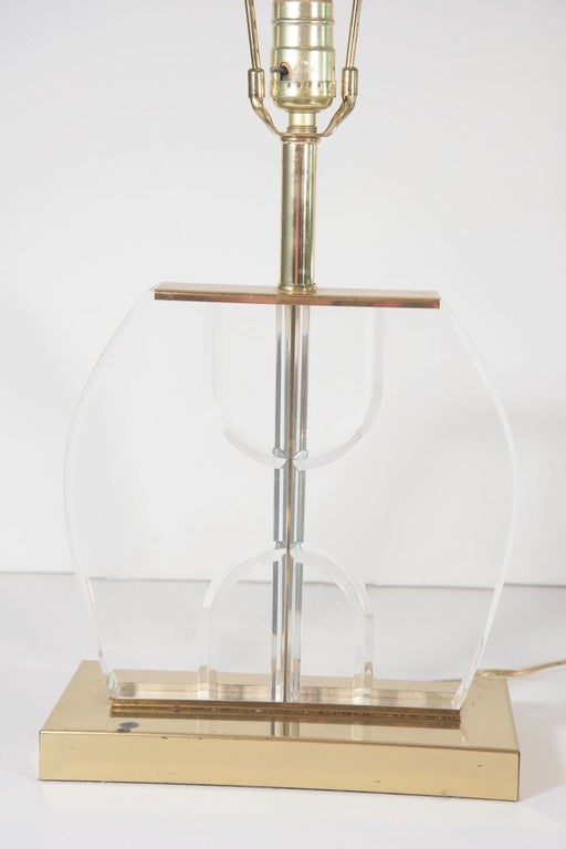 A pair of vintage, highly modernistic table lamps, produced circa 1970s, with central brass stems, inset within decorative Lucite panels, and rectangular top and base in plated brass. Wiring to US standard, each requires a single Edison base bulb.