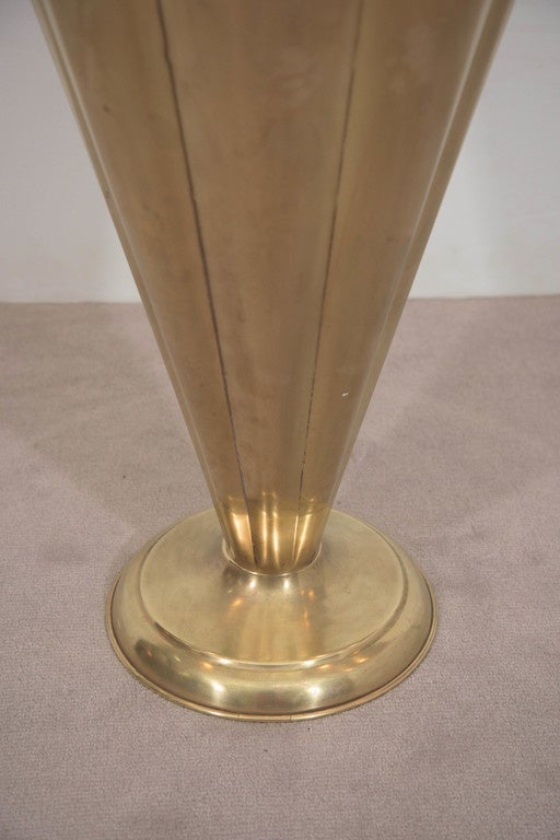 A whimsical brass umbrella stand, produced in Italy, circa 1950s, with a curved decorative handle over a body designed as an overturned umbrella or parasol, with beading along the pleated edge, on a circular base. Very good vintage condition, with