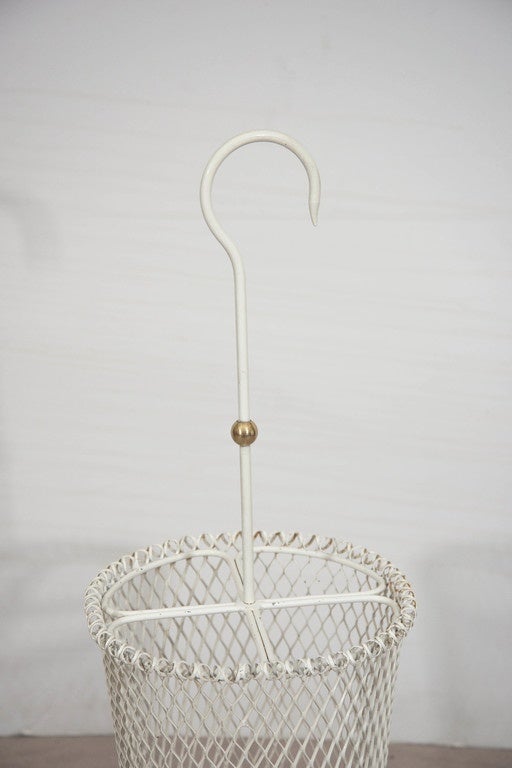 A French, vintage umbrella stand, produced circa 1950s by Hungarian-French designer Mathieu Matégot, whimsically shaped to resemble an umbrella, in white enameled metal, with curved decorative handle and brass accent bulb, over a perforated body