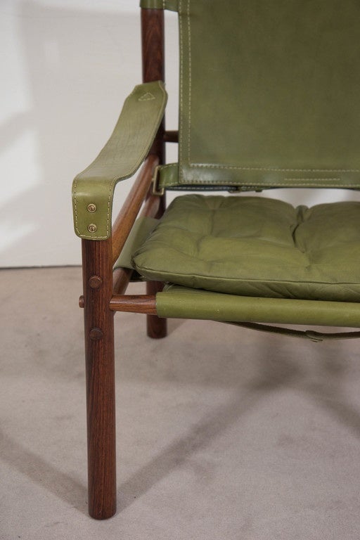 A pair of vintage 'Sirocco' safari chairs, produced circa 1960s by Swedish designer Arne Norell for Möbel AB Arne Norell of Aneby, Sweden, with tufted loose seats, backs and armrests in beautifully aged green leather, with stitching accents along