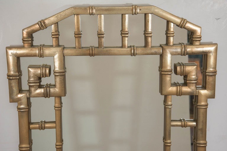 A vintage pair of faux bamboo wall mirrors, styled in the chinoiserie mode, produced circa 1960s, the mirror inset beneath a fretwork giltwood frame, with antiqued finish. Good vintage condition, with minimal wear to gilded surface, consistent with