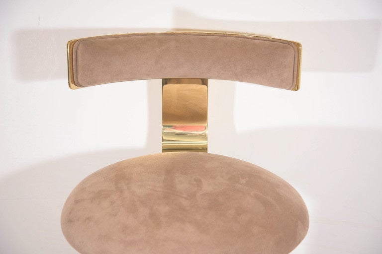 A set of three bar stools, produced circa 1980s by Design For Leisure, each with cushioned seat and back, upholstered in beige suede against a highly modernistic brass frame, the rotating seat set above a single, channeled brass, column form base on