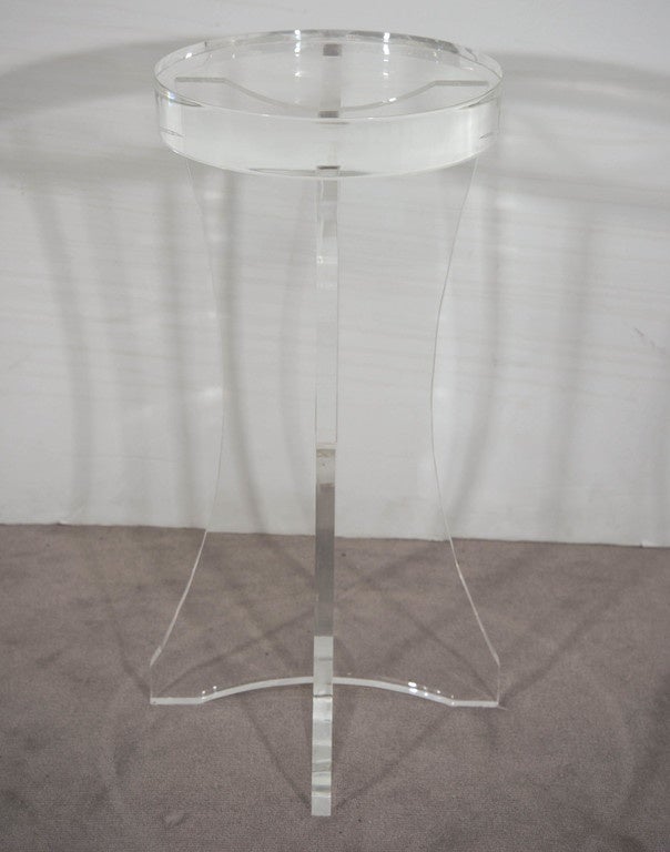 A vintage pedestal and accent table, in transparent Lucite acrylic with thick round top on a curved, cross form panel base. Very good condition, consistent with age and use.