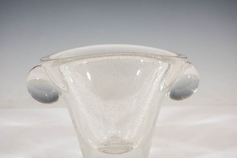 A vintage glass vase, produced between the 1940s and 1950s by Daum Glass Studio of Nancy, France, with controlled bubbles applied to the body and wide, oval form rim, flanked by clear globe handles. Very Good vintage condition, consistent with age