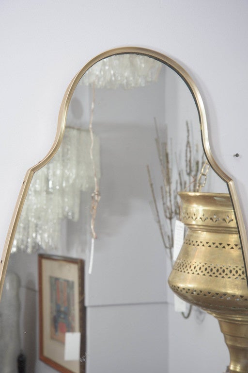 A pair of vintage wall mirrors, produced in the United States circa 1960s, with mirrors inset within brushed brass ogee shaped frames. Good condition with age appropriate wear, minor scratches to frames and slight paint scuffs to one of the mirror