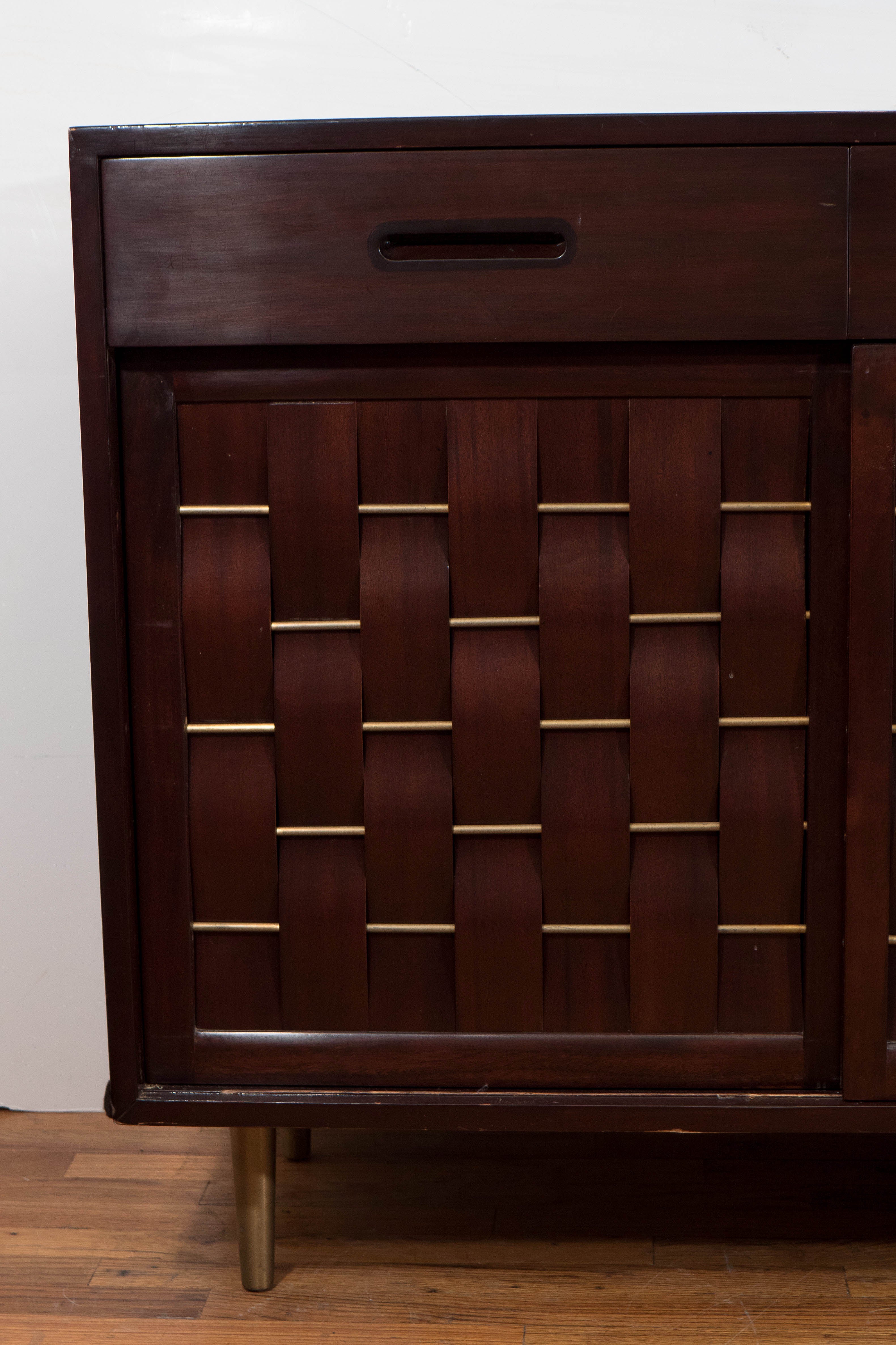 A vintage mahogany credenza, produced circa 1950s by designer Edward Wormley for Dunbar Furniture, with three drawers with recessed pulls, above cabinet space, inset with a center shelf and six adjacent interior drawers, with three sliding doors