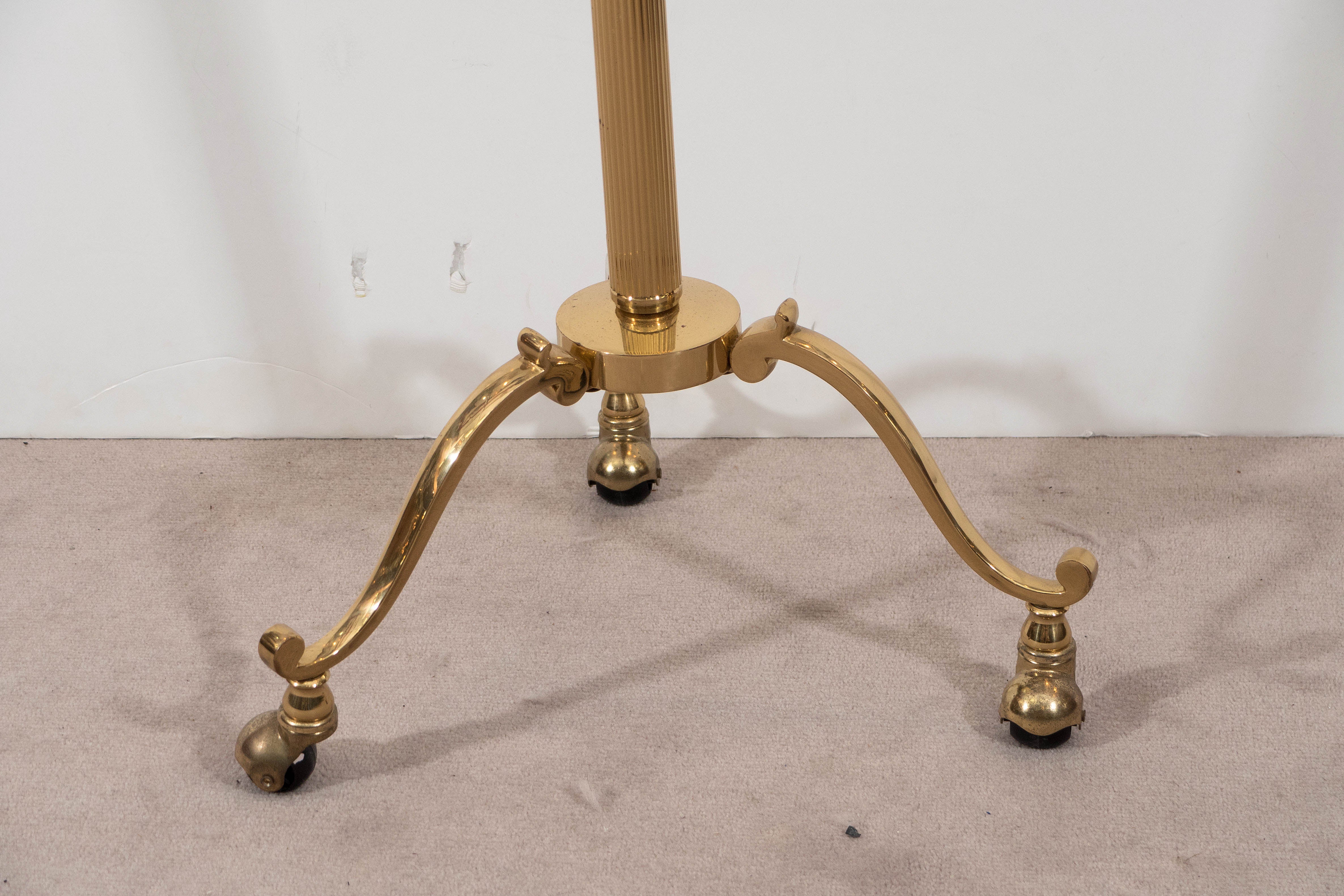 A vintage valet, produced in Italy, circa 1960's, in polished brass, with black painted wood hanger and leather lined coin tray, on tripod base with cabriole legs and casters. Very good vintage condition, consistent with age and use, with minimal