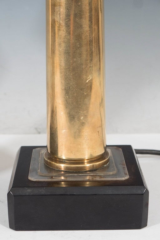 A pair of circa 1940's vintage table lamps, made of a 15 millimeter brass artillery shell casings, used during the second World War, standing on a square black celluloid base; included are on/off switches, affixed to the brass bodies, and black