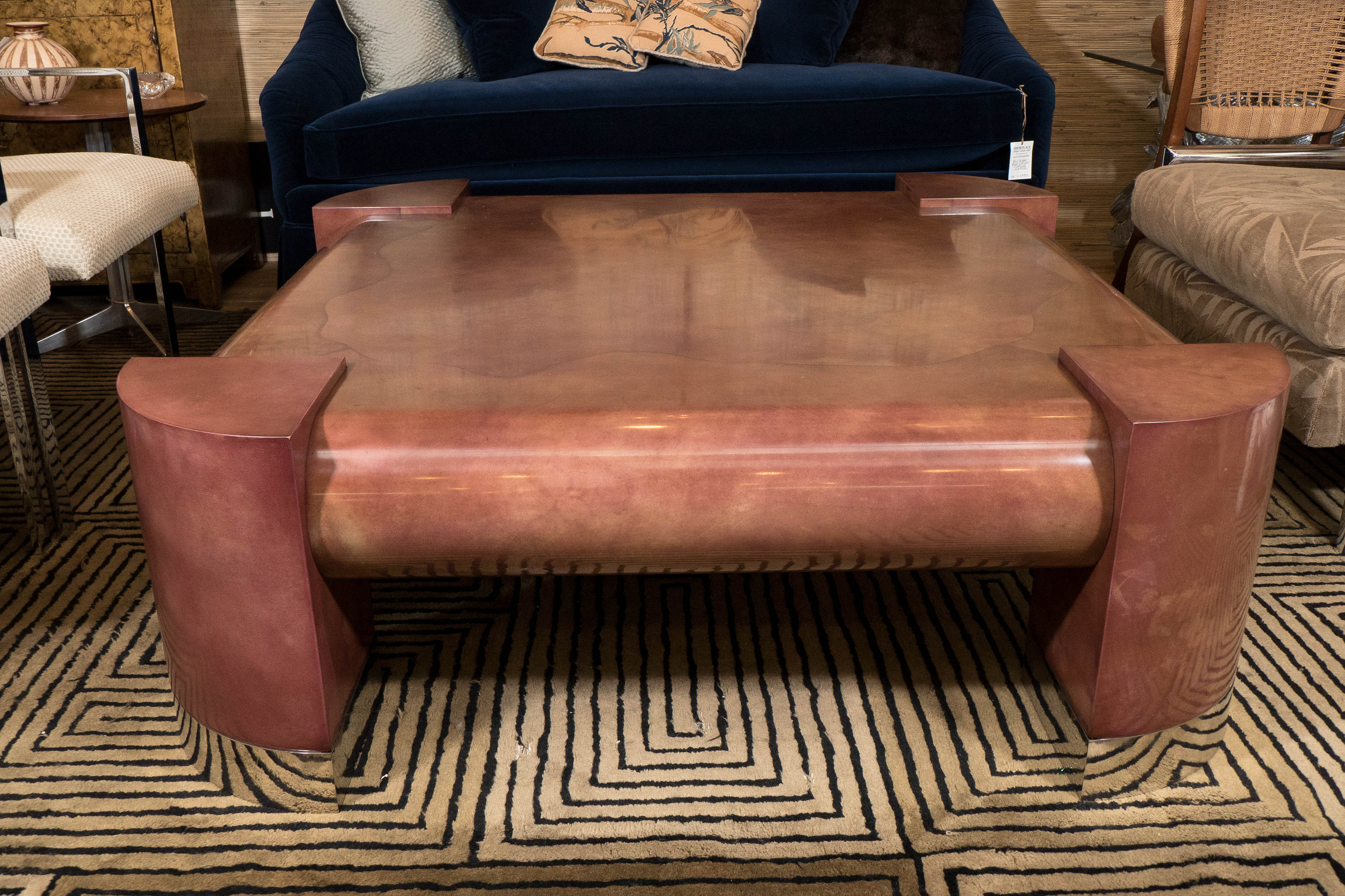 A vintage, highly modernistic coffee table, designed by Lorin Marsh, circa 1970s, in the manner of Karl Springer, in rouge toned lacquered goatskin, on rounded quarter wedge form legs with stainless steel plates. Markings include original label to