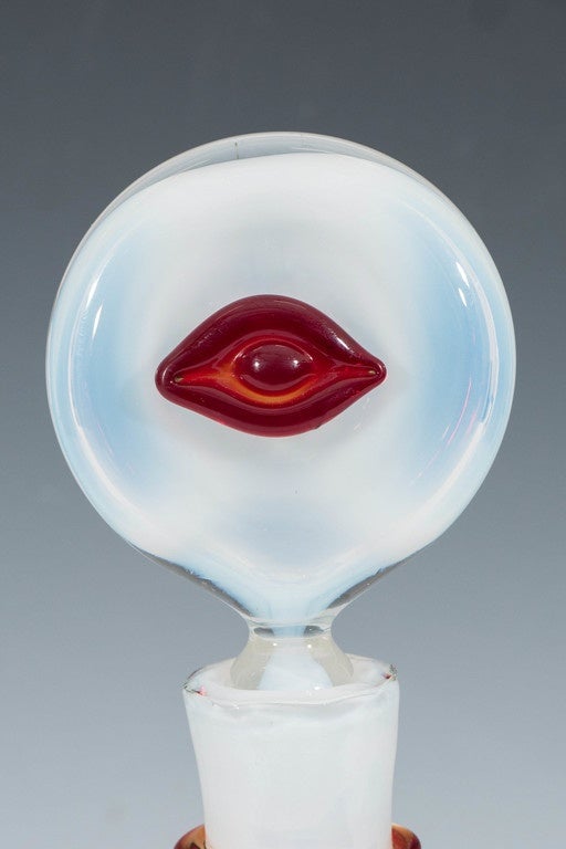 A vintage, very rare baluster form decanter by designer Wayne Husted, in opalescent blown glass, with a red band wrapped around the neck; included is a disc shaped stopper, with a decorative red prunt in the form of an eye. This decanter is in very