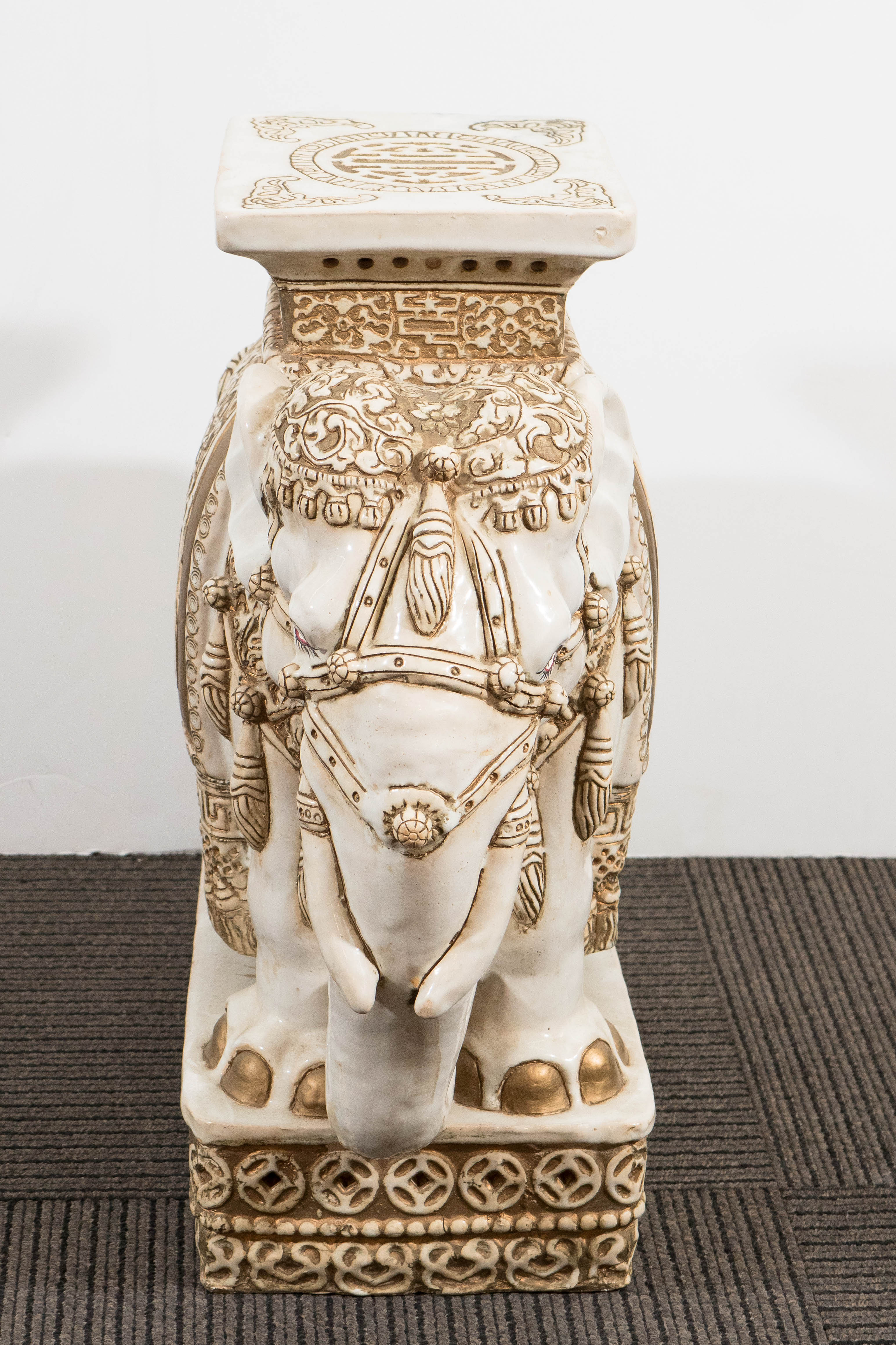 A vintage pair of glazed ceramic sculptural elephant garden stools, in off-white color with gold details, incised with all-over pattern. Good vintage condition, some stains and a small crack on the surface of the ‘belly’ of one of the elephants. Can