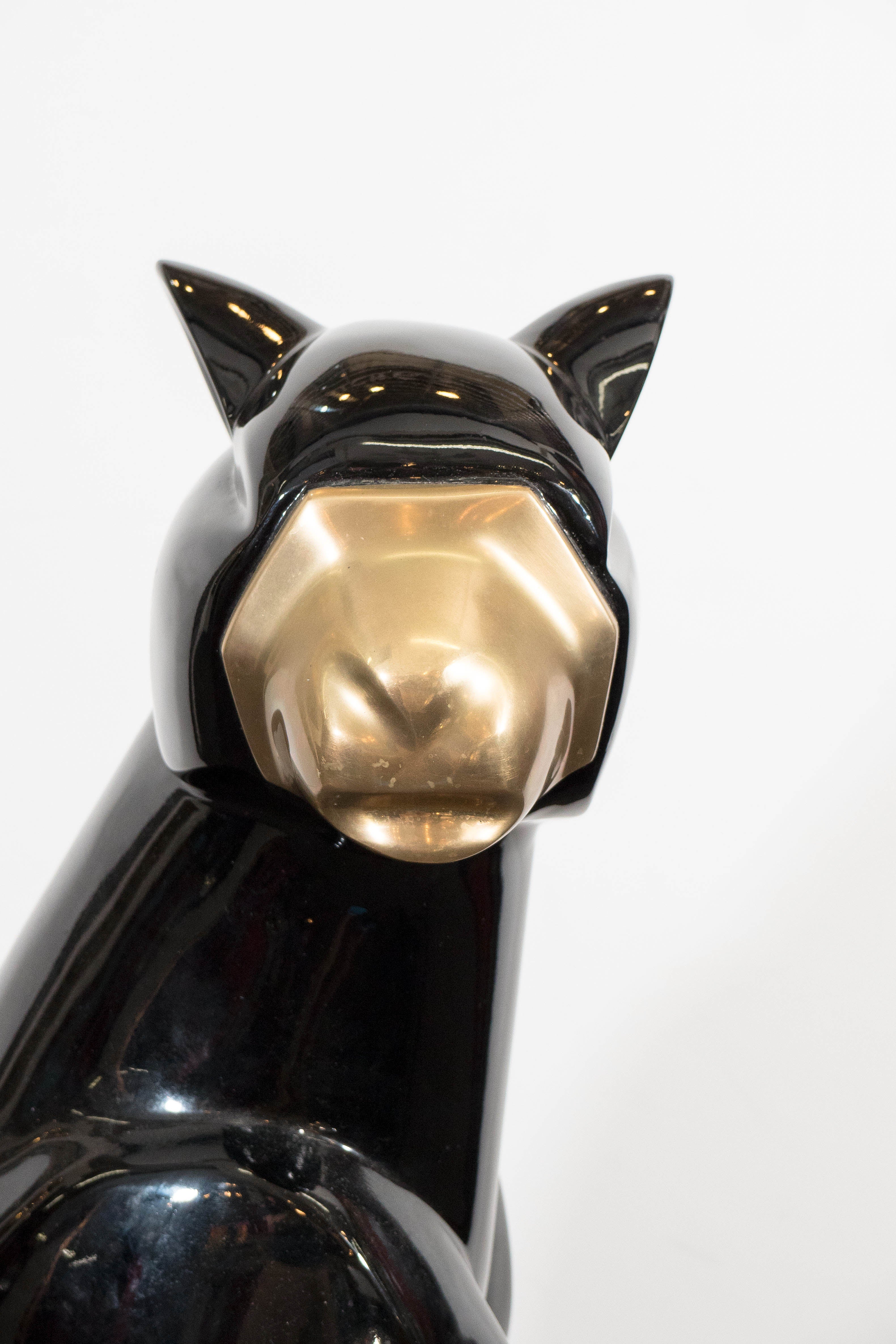Pair of sculptural black cats in an Egyptian, Art Moderne style, with gilded faces and tails. Weighted body. Good condition with minimal chips to the black surfaces.