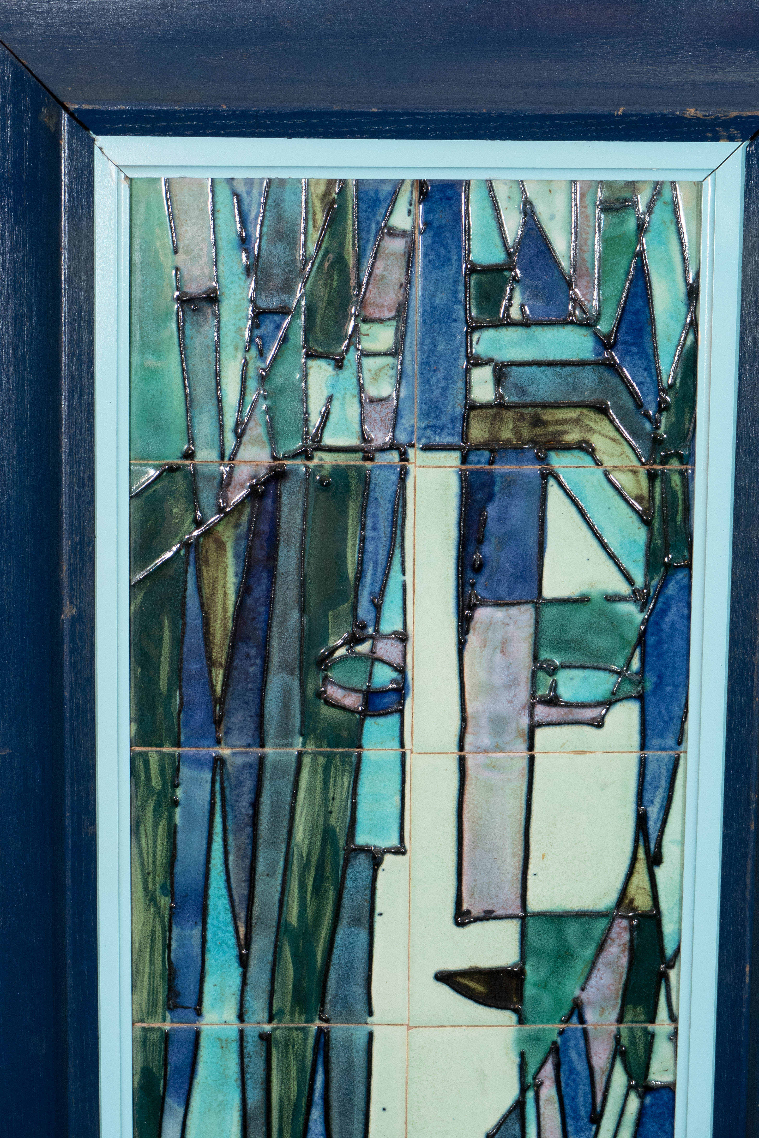 A pair of ceramic art tile plaques, by American artist and ceramicist Harris Strong, circa 1960's, featuring Cubist depictions of a man and woman, in shades of green, blue and purple glaze, each piece within an individual, painted wood frame.