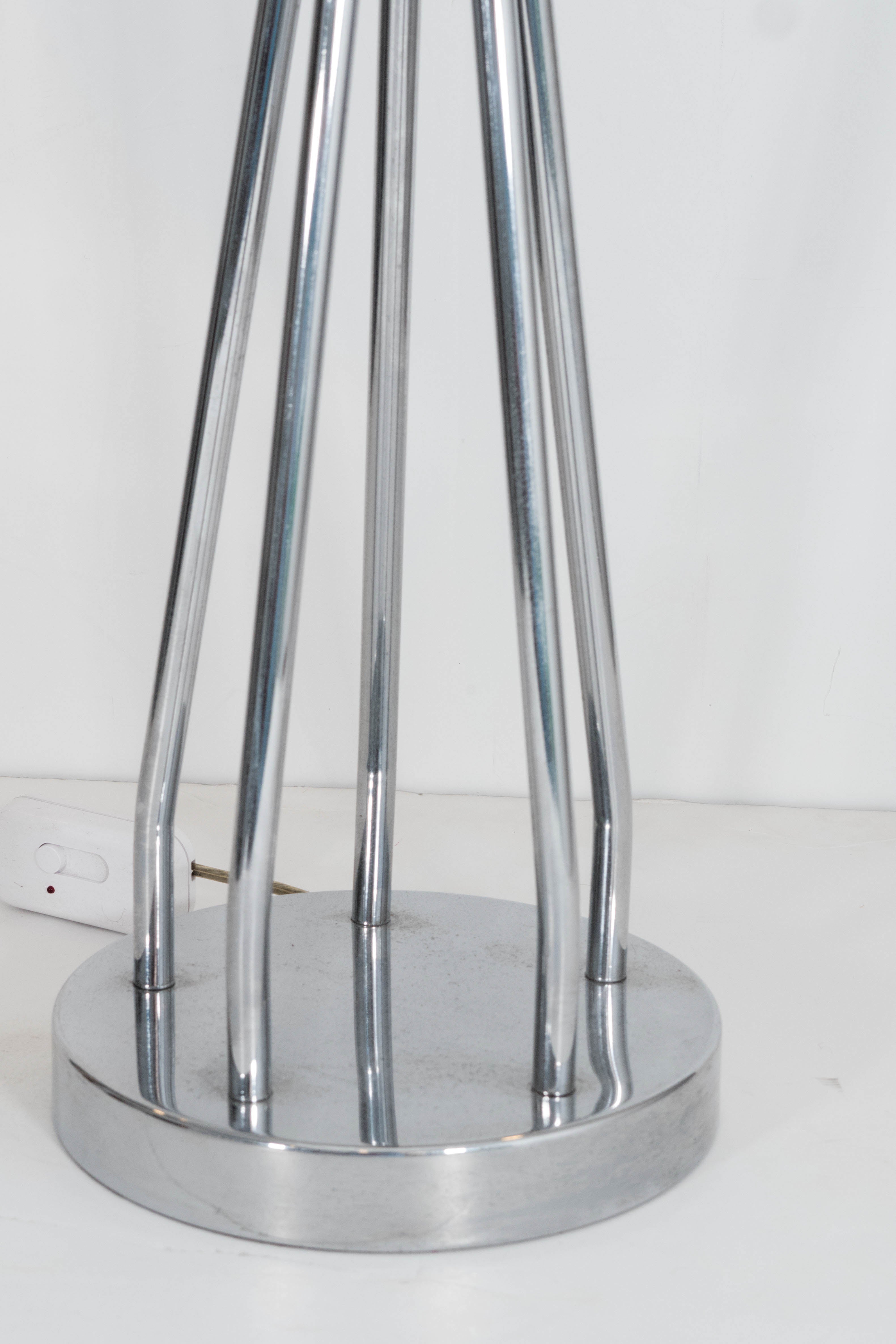 A vintage pair of highly modernistic table lamps, each with a round white globe shade in milk glass, above spire legs and a circular base in polished chrome. Wiring to US standard; includes on/off switch along the extension cord. Very good