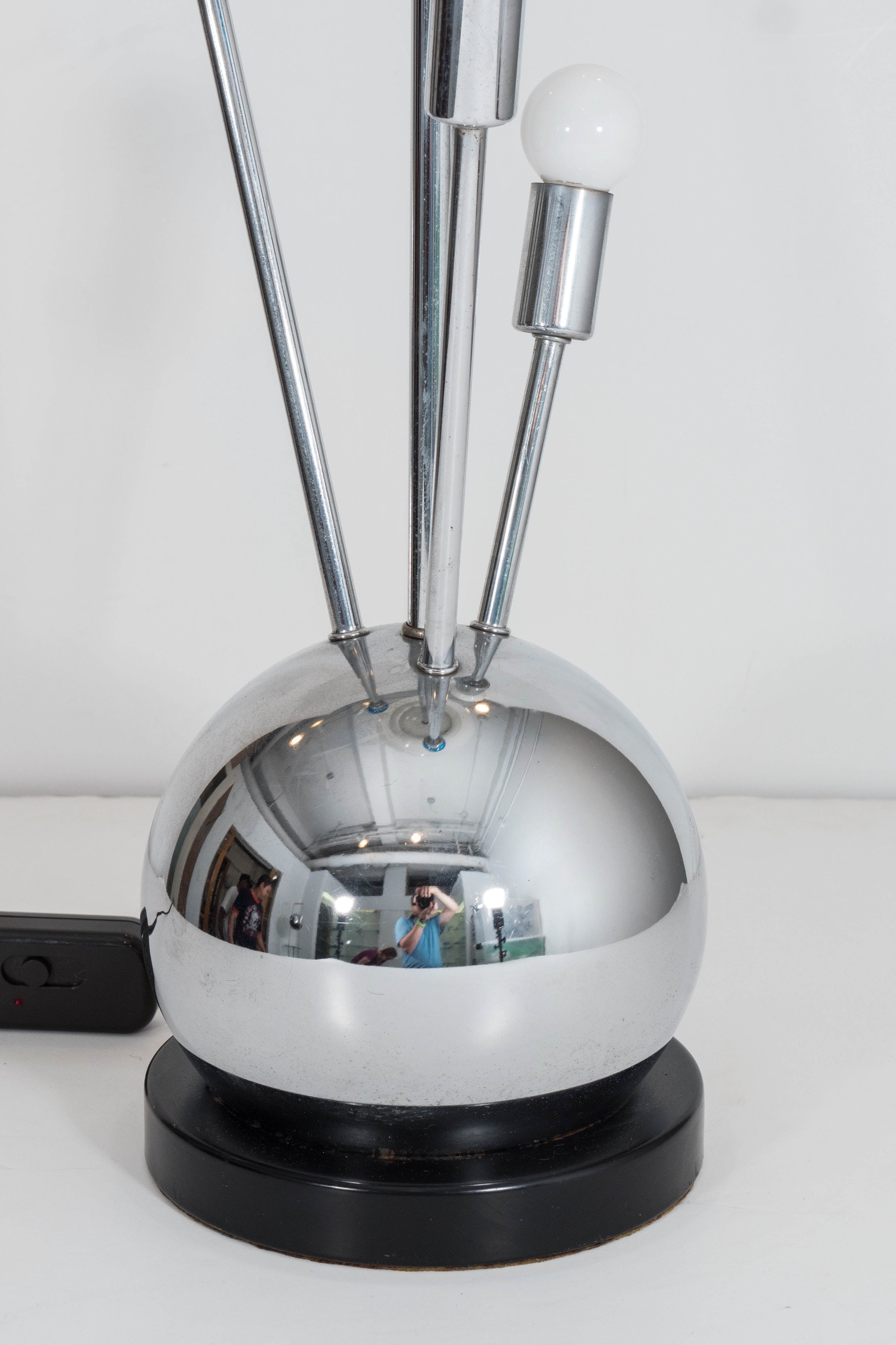 A pair of vintage 1950s table lamps, by Laurel Lamp Co., each with a large, centralized white glass globe shade on a single chrome stem, surrounded by smaller arms of varying lengths, radiating from a highly polished dome base, on a black lacquer,