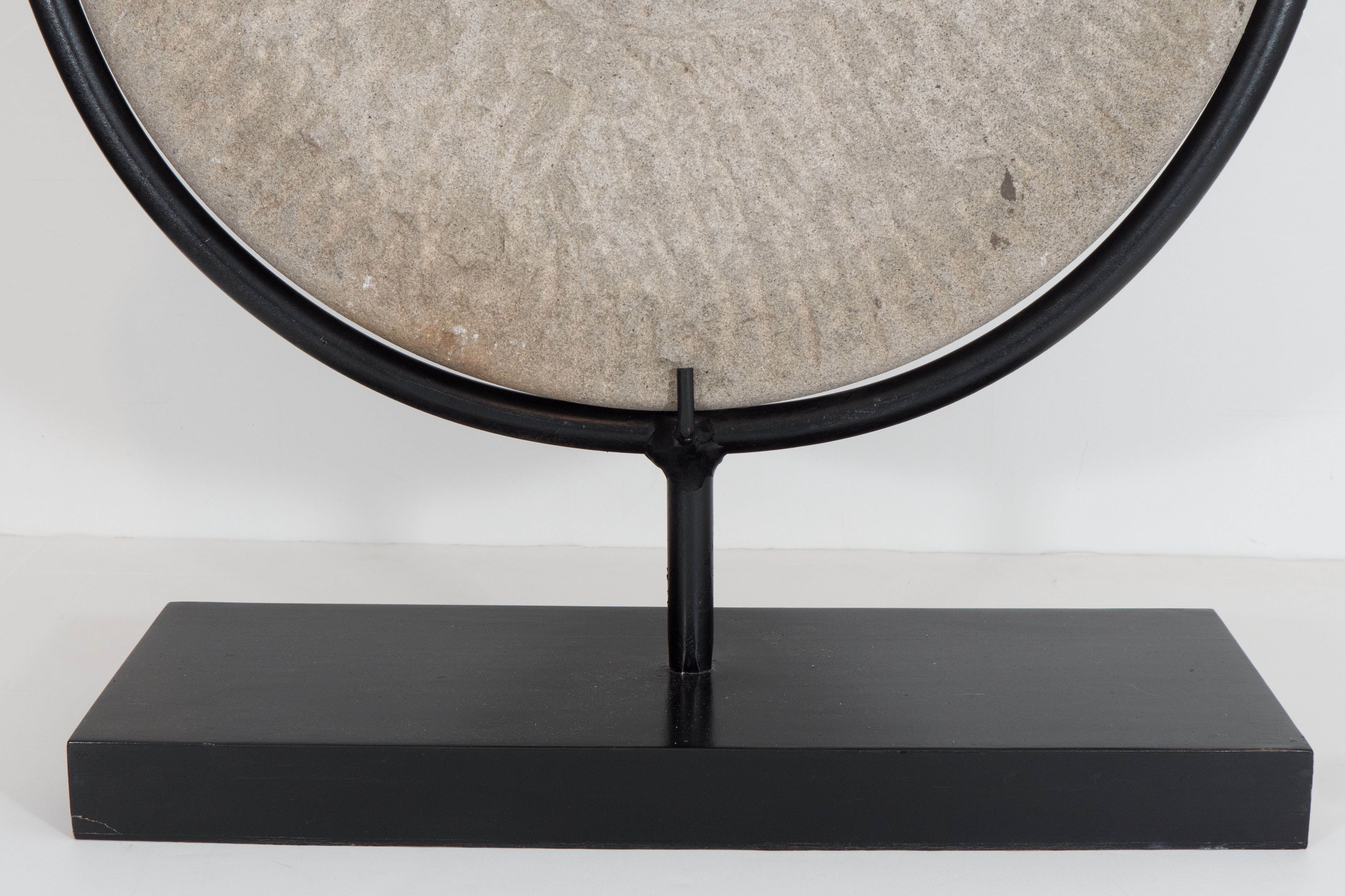 An antique Chinese millstone, otherwise stone grinding wheel, produced and utilized, circa late 19th century, the wheel stands upright on a decorative display. Good antique condition, marks and wear consistent with age and use.