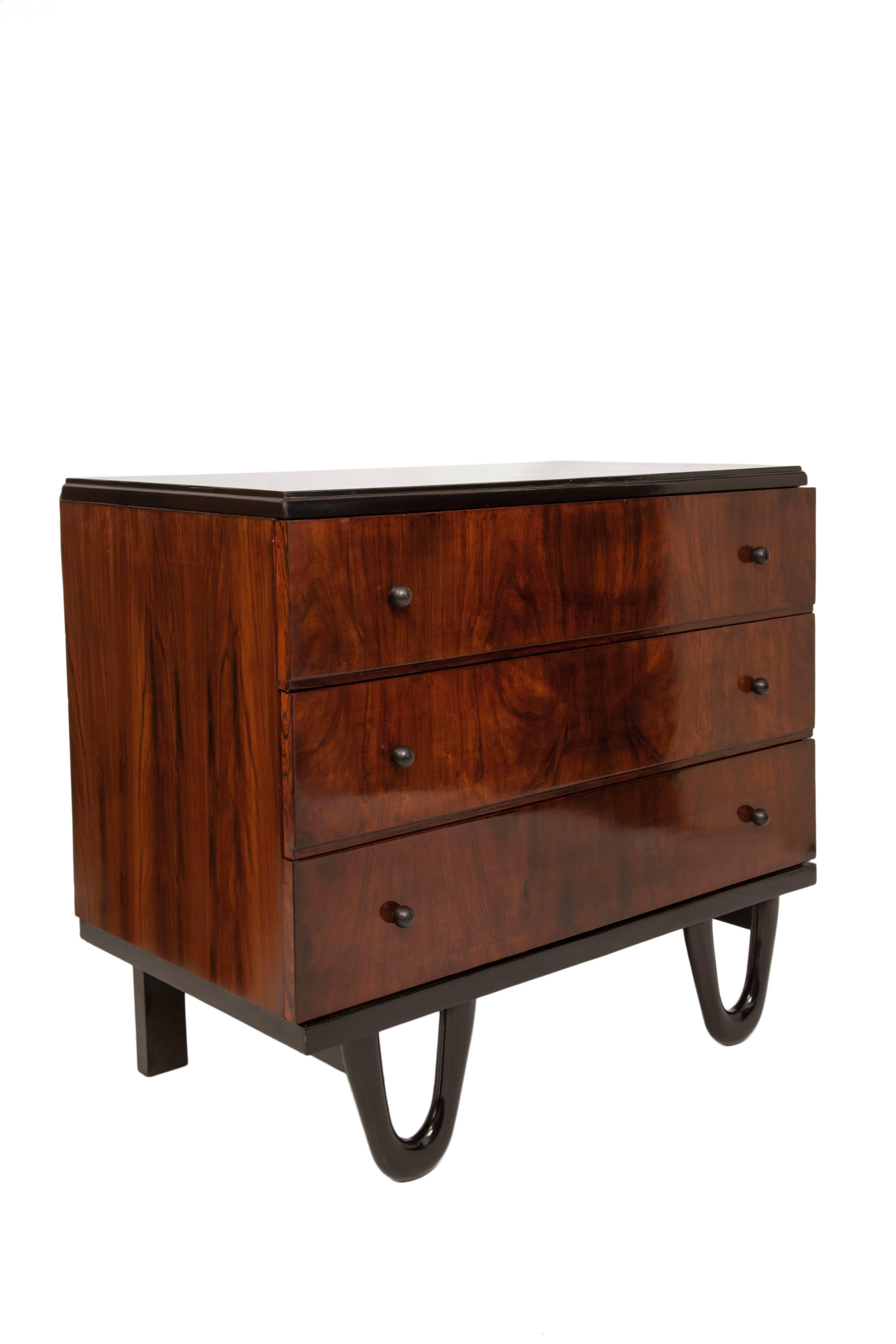 A small scale vintage chest of drawers, produced circa 1960s, in Brazilian jacaranda wood, with three exterior drawers, each with round knob pulls, on unusually looped feet to the front. Very good vintage condition, consistent with age and use.