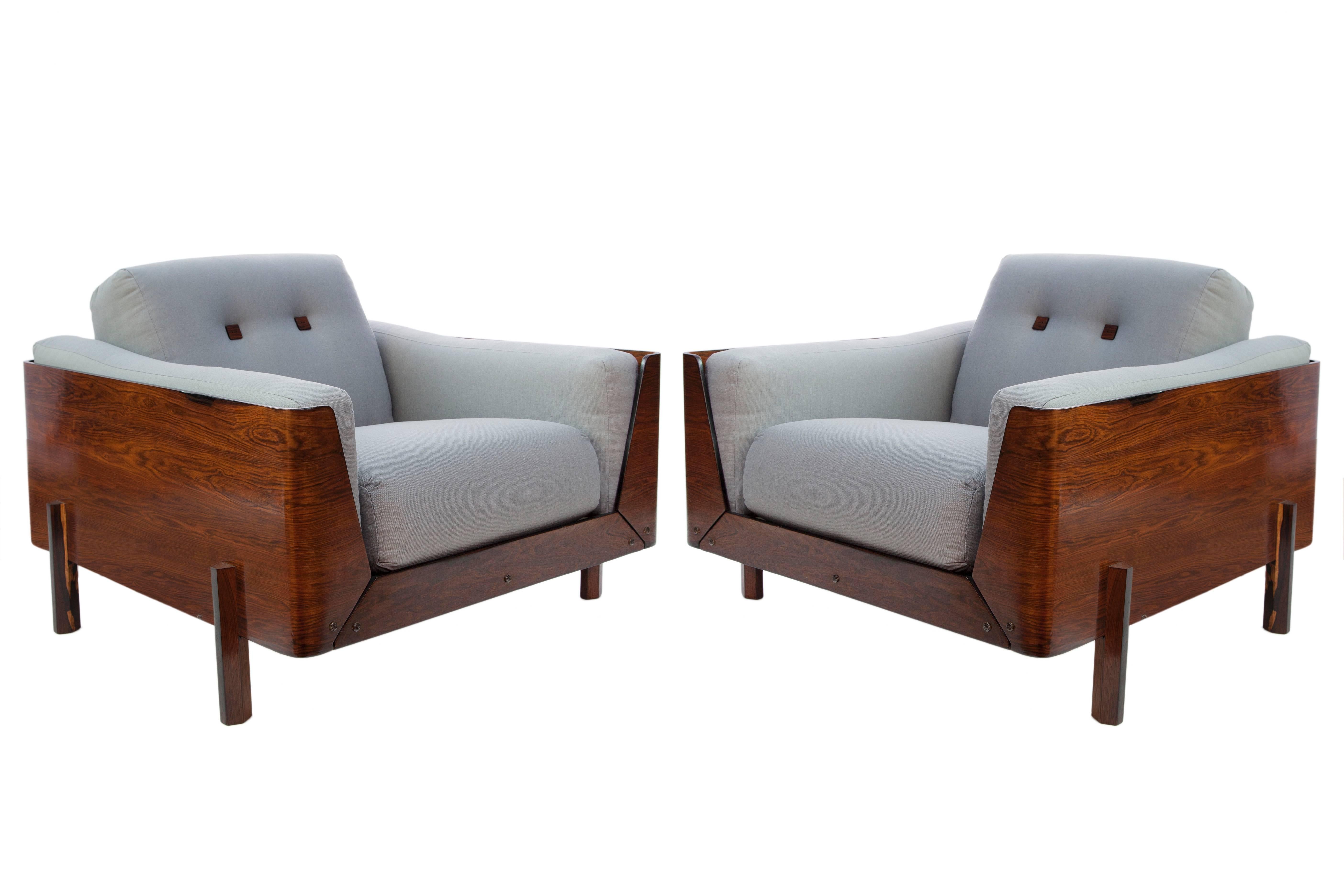 A vintage pair of armchairs, produced in Brazil, circa 1960s, attributed to designer Jorge Zalszupin, with plush cushioned seats, arms and backs, upholstered in grey linen and tufted with square wood buttons, inset within a wonderfully modernistic