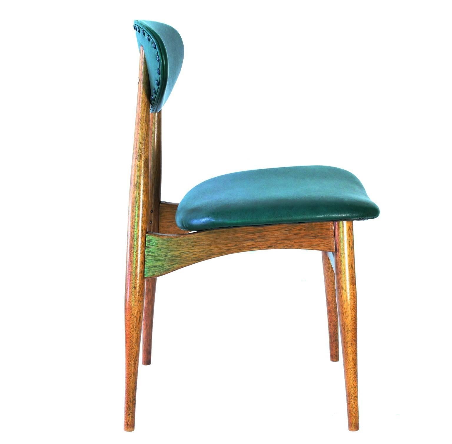 A vintage set of four teakwood dining chairs, produced in Denmark, circa 1950s, each with unique fasteners, connecting the tapered legs and horizontal supports. Comfortable and sturdy, the backs and seats were recently reupholstered in vinyl,
