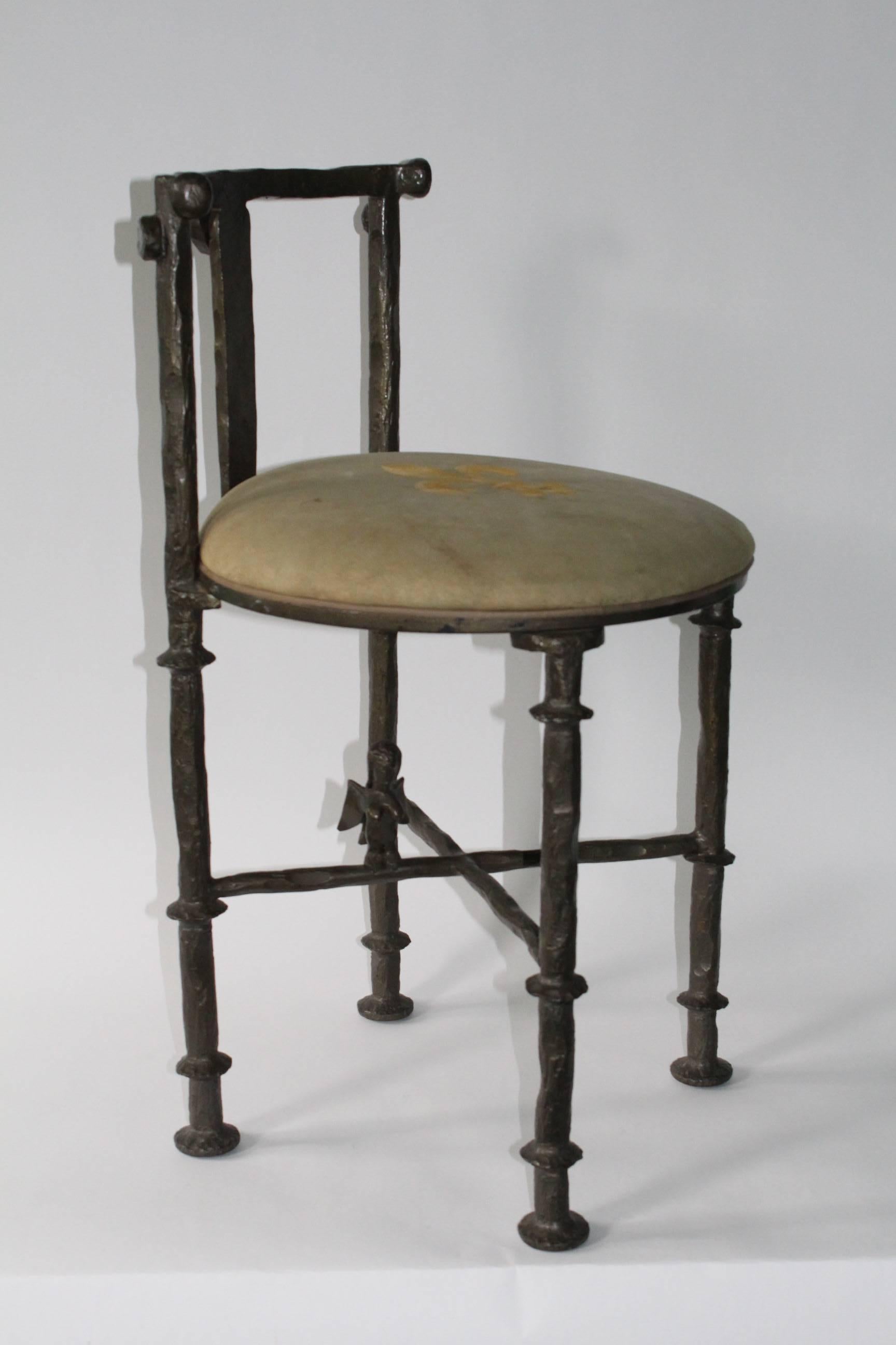 This fantastic stool, designed in the manner of Swiss sculptor Diego Giacometti, includes a Brutalist style frame in hammered and artfully formed patinated steel, the lengthy curved back and cushioned seat with fleur-de-lis on four legs, joined by a