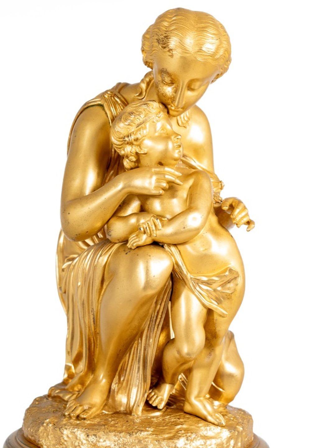 Reloj Figural de Ormolu estilo Luis XVI, finales del siglo XIX, representando a una Afrodita agachada con Cupido, sobre la esfera circular esmaltada, movimiento de campana, pedestal acanalado montado con coronas de acanto y laurel, centrado por una