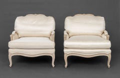 Par de bergères de madera ceruseada tapizadas en tela blanca, estilo Luis XV