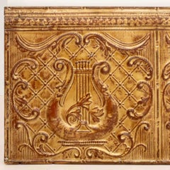 Pannello con motivo musicale in metallo dorato a tema architettonico