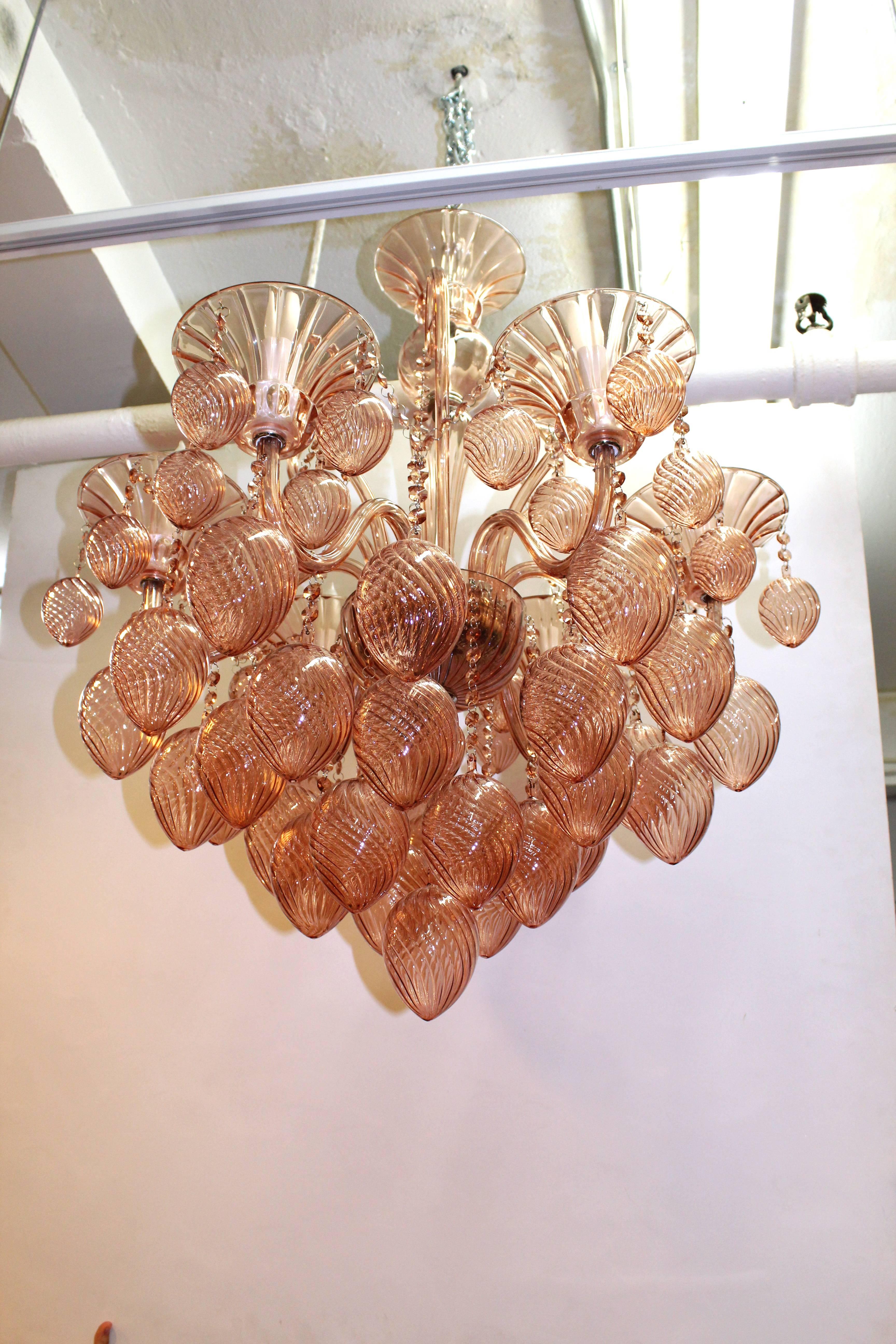 A peachy pink Murano glass chandelier with six lights. Embellished with multiple swirled baubles and glass beads.

110635

