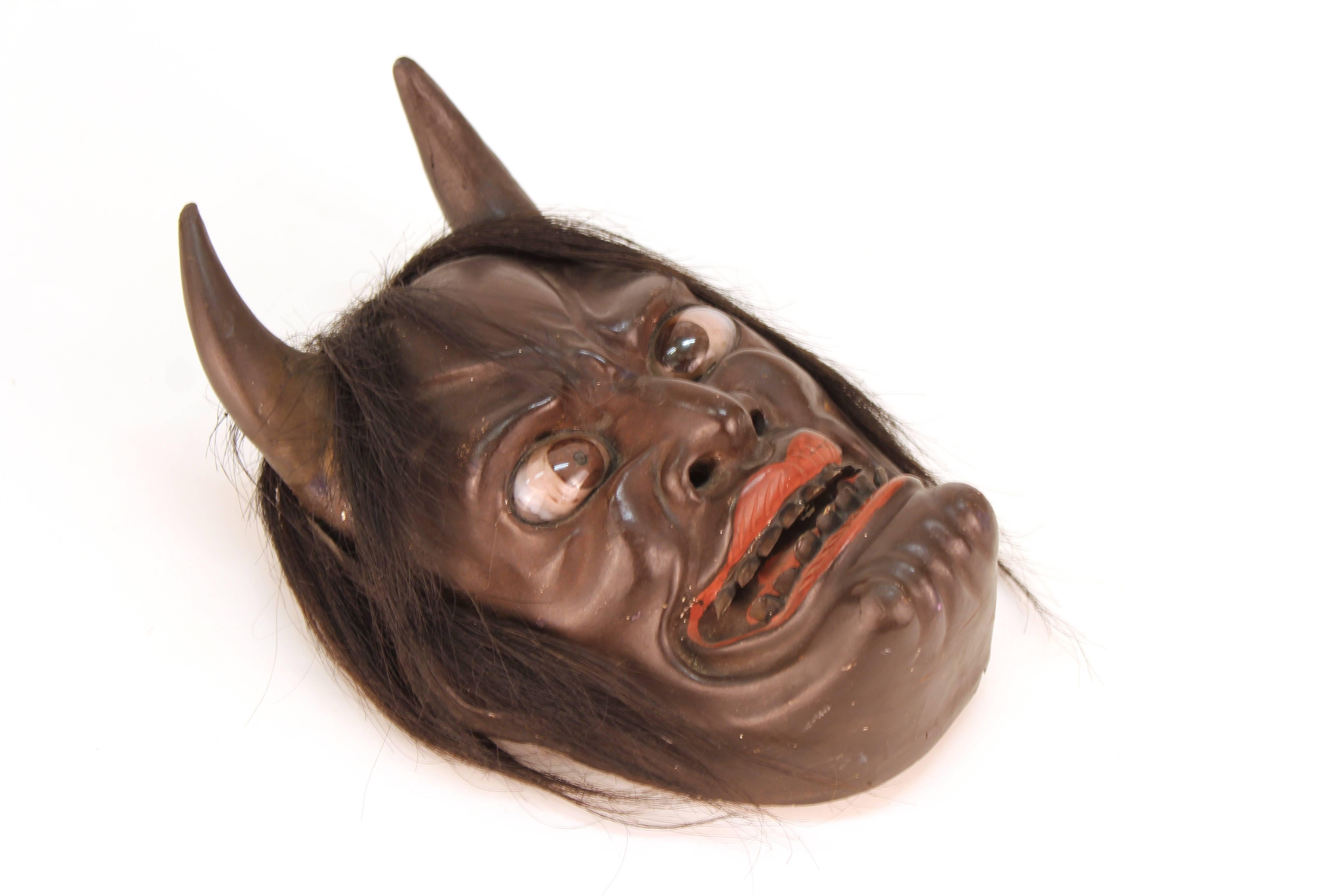 Eine japanische Ike-Maske aus Holz, die in der Edo-Zeit (1603-1868) um 1850 hergestellt wurde und ein Teufelsgesicht darstellt. Die Maske ist sehr detailliert und hat eingefügte Augen und Haare, die an ihr befestigt sind.