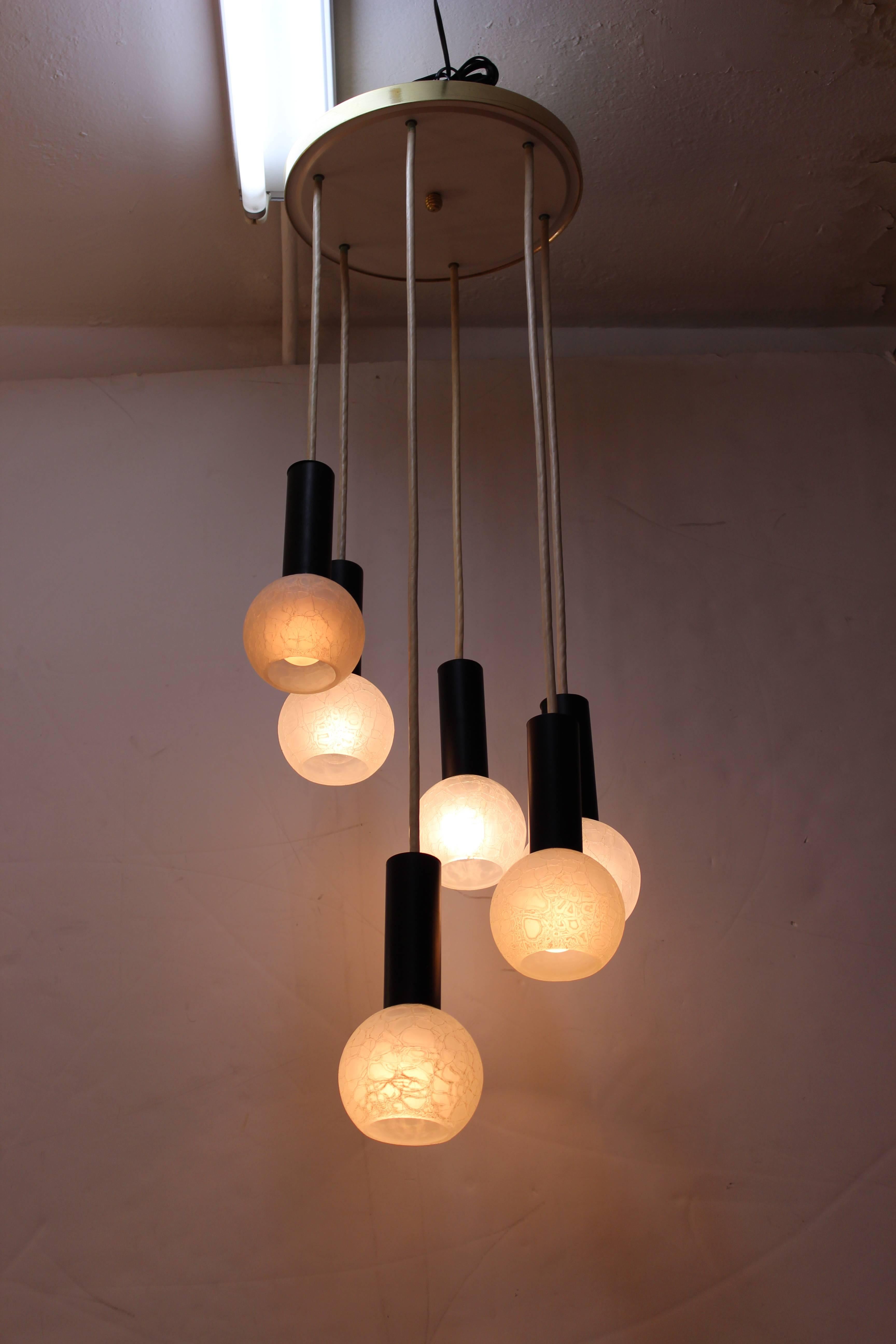 A Mid-Century Modern chandelier with cascading individual pendants with etched glass globes, hanging from a circular ceiling mount. The piece is in great vintage condition.