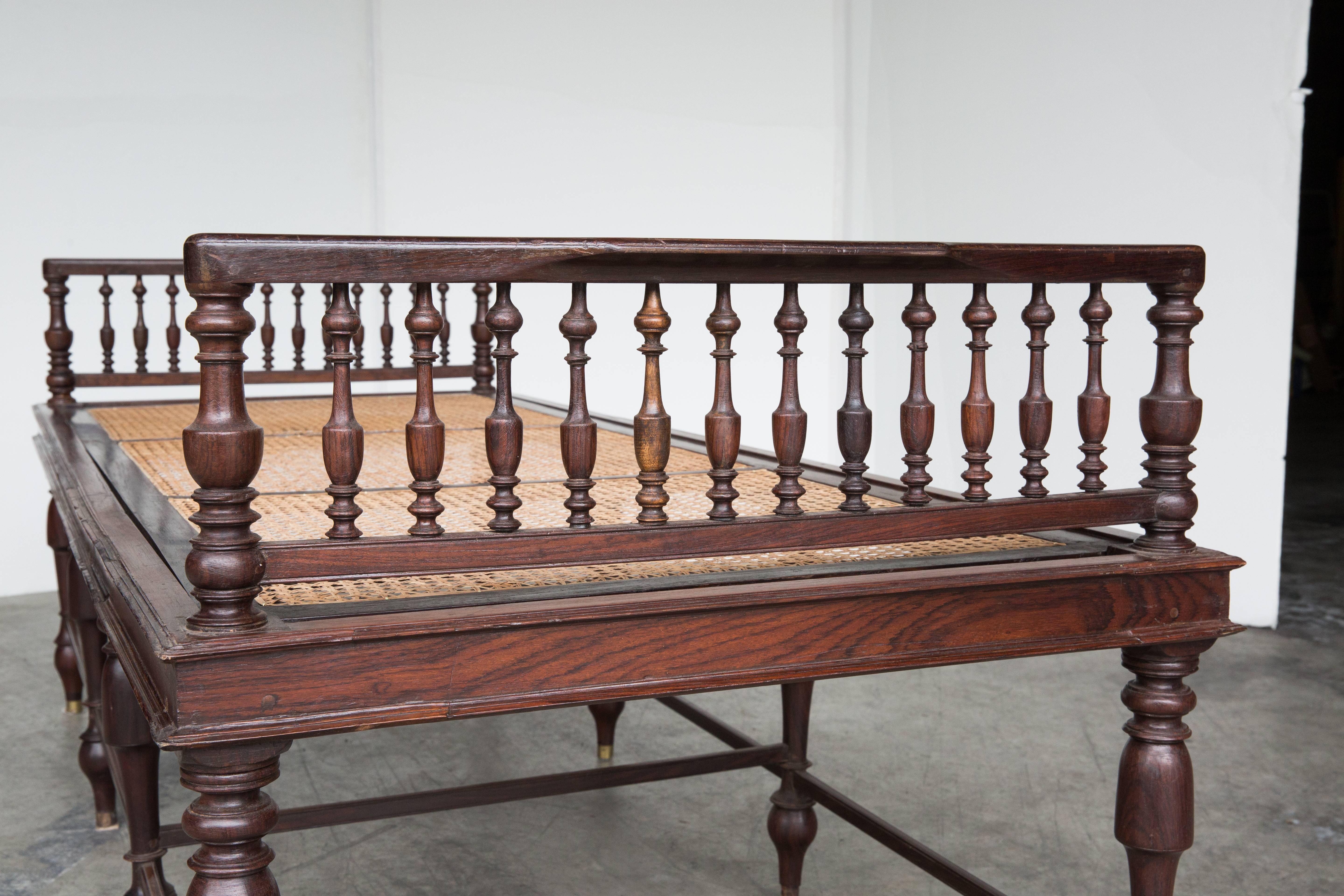 An Anglo-Indian daybed made from rosewood with a newly caned seating area. The headboard and footboard have turned wood spindles as well as the legs. 

The interior dimensions are 71