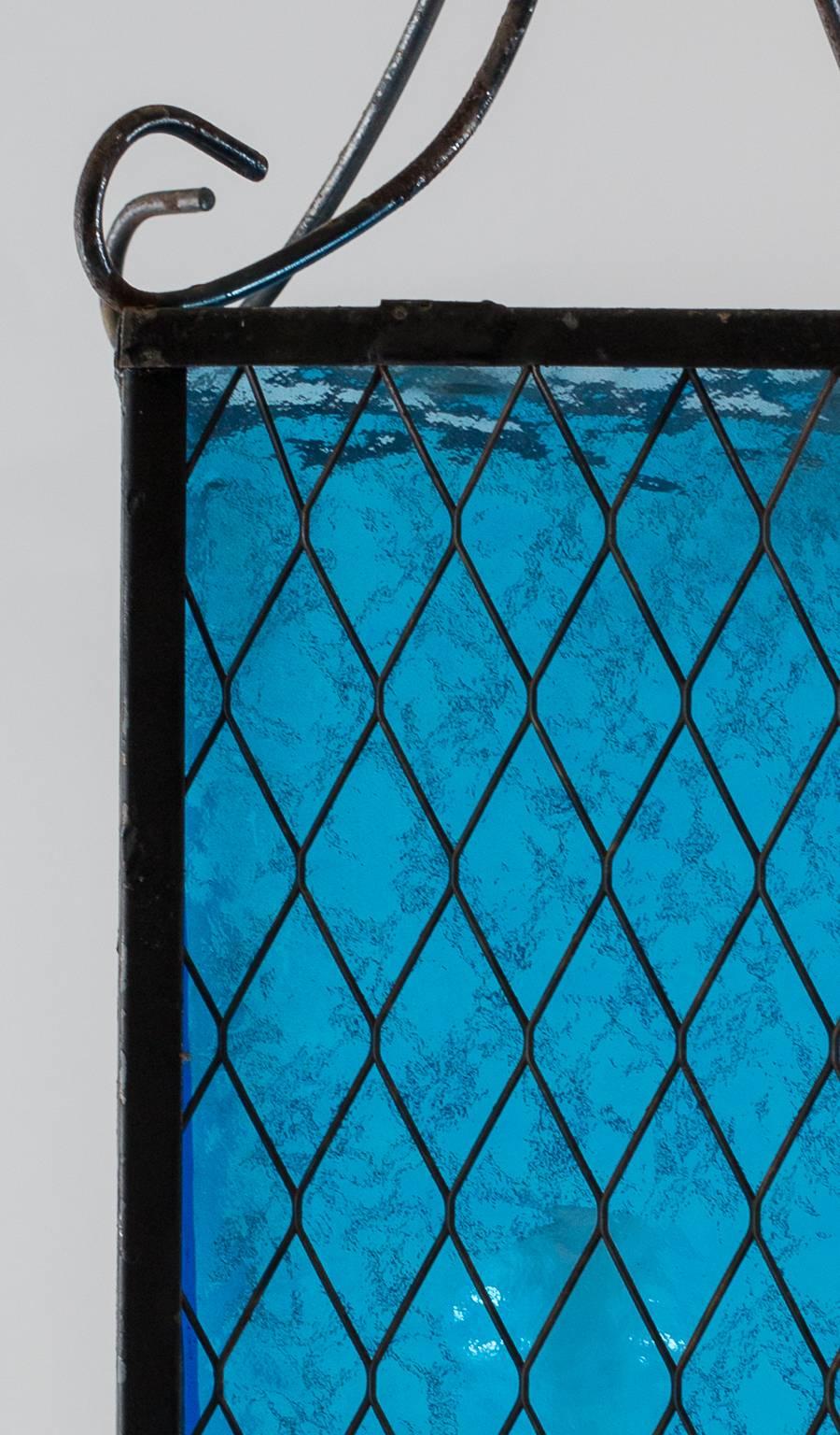 Schmiedeeisenarbeiten für den Rahmen. Rechteckiger umrahmter blauer Blasenglas-Schirm. Eine Standard-Glühbirne in der Mitte. Verkabelt für die Beleuchtung des 20. Jahrhunderts.