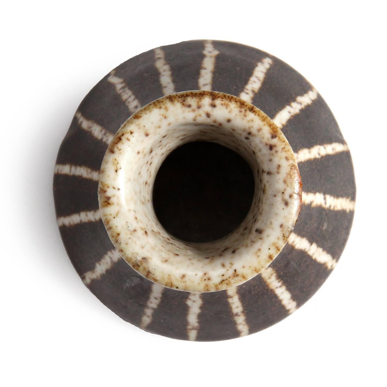 An expressive ceramic waisted vase, having a rich mocha glaze with cream striping.