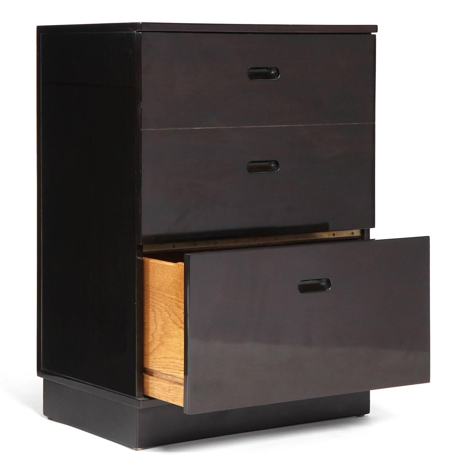 An ebonized and polished dark mahogany telephone cabinet or vanity table having a storage drawer and an innovative fold-out bench.