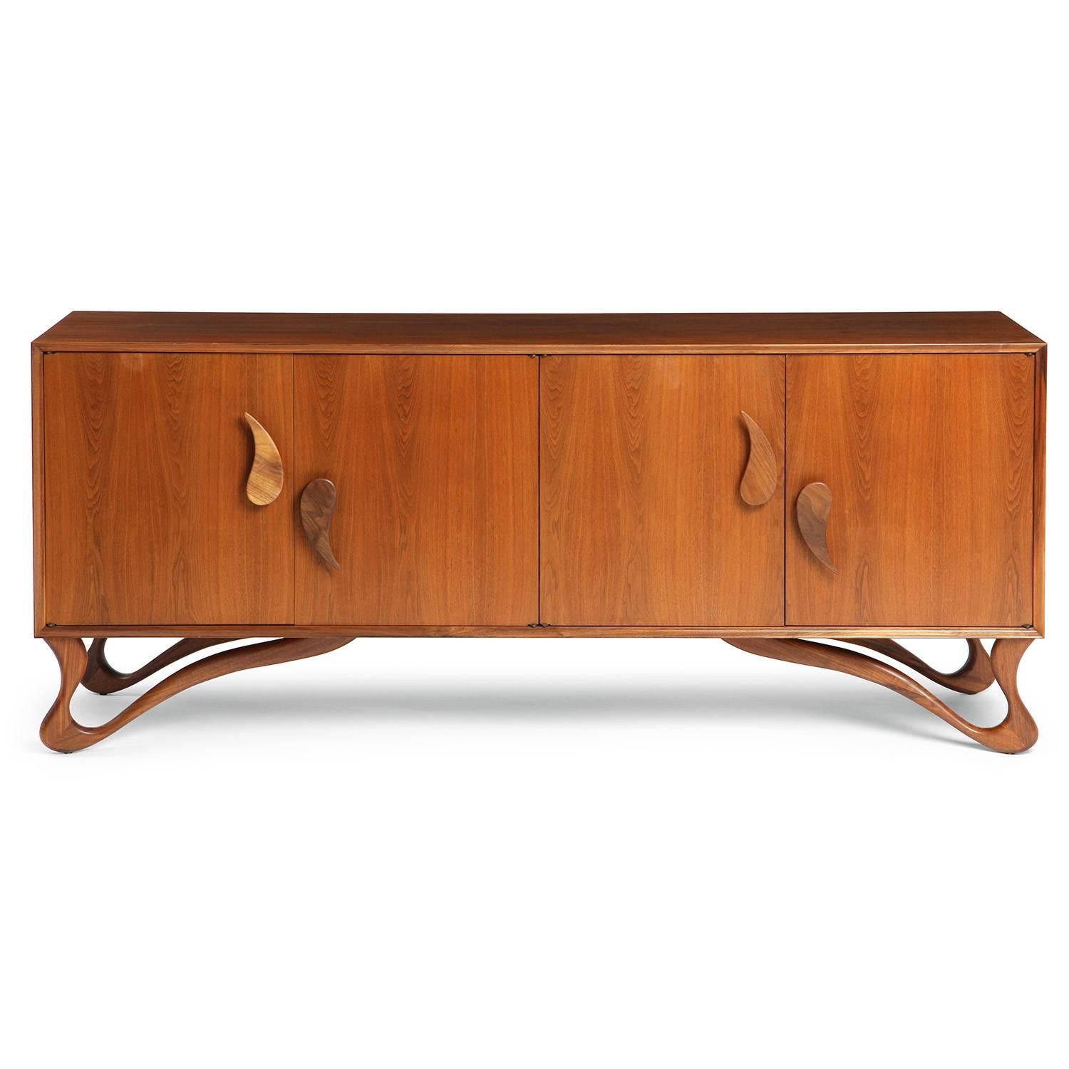 A well scaled and highly sculptural sideboard having a four door case with carved teardrop form handles floating on scrolling biomorphic legs.