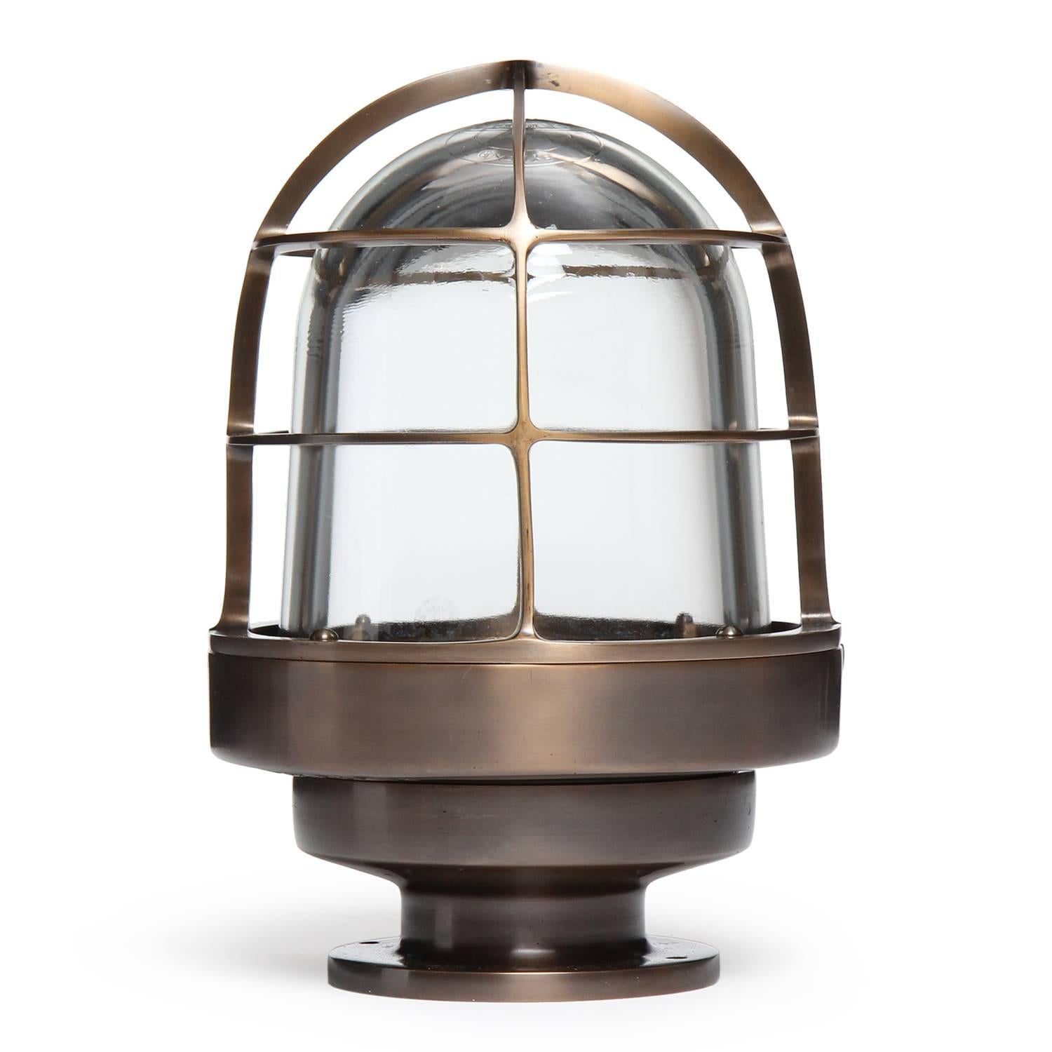 A substantial domed caged flush mount industrial bronze light fixture having a warm patina and a glass inner dome diffuser.
