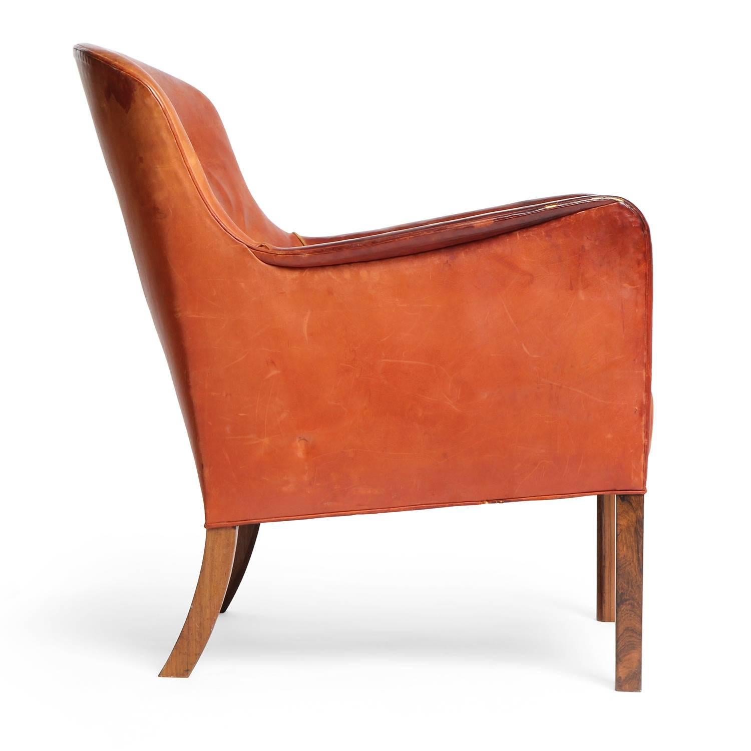 A button tufted lounge chair in the original leather upholstery with rosewood legs.