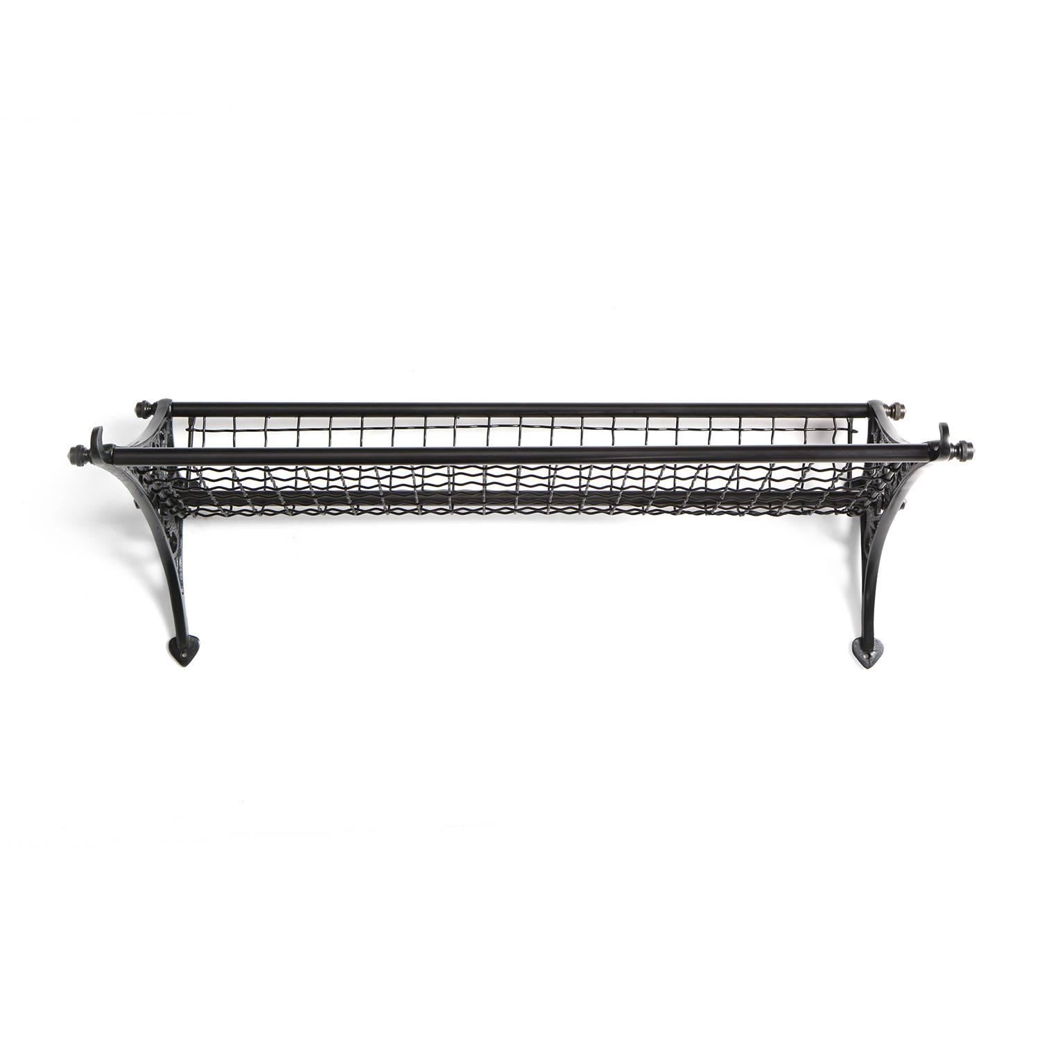 A finely crafted patinated cast iron train rack having expressive scrolling open fretwork sides and a woven metal mesh surface.