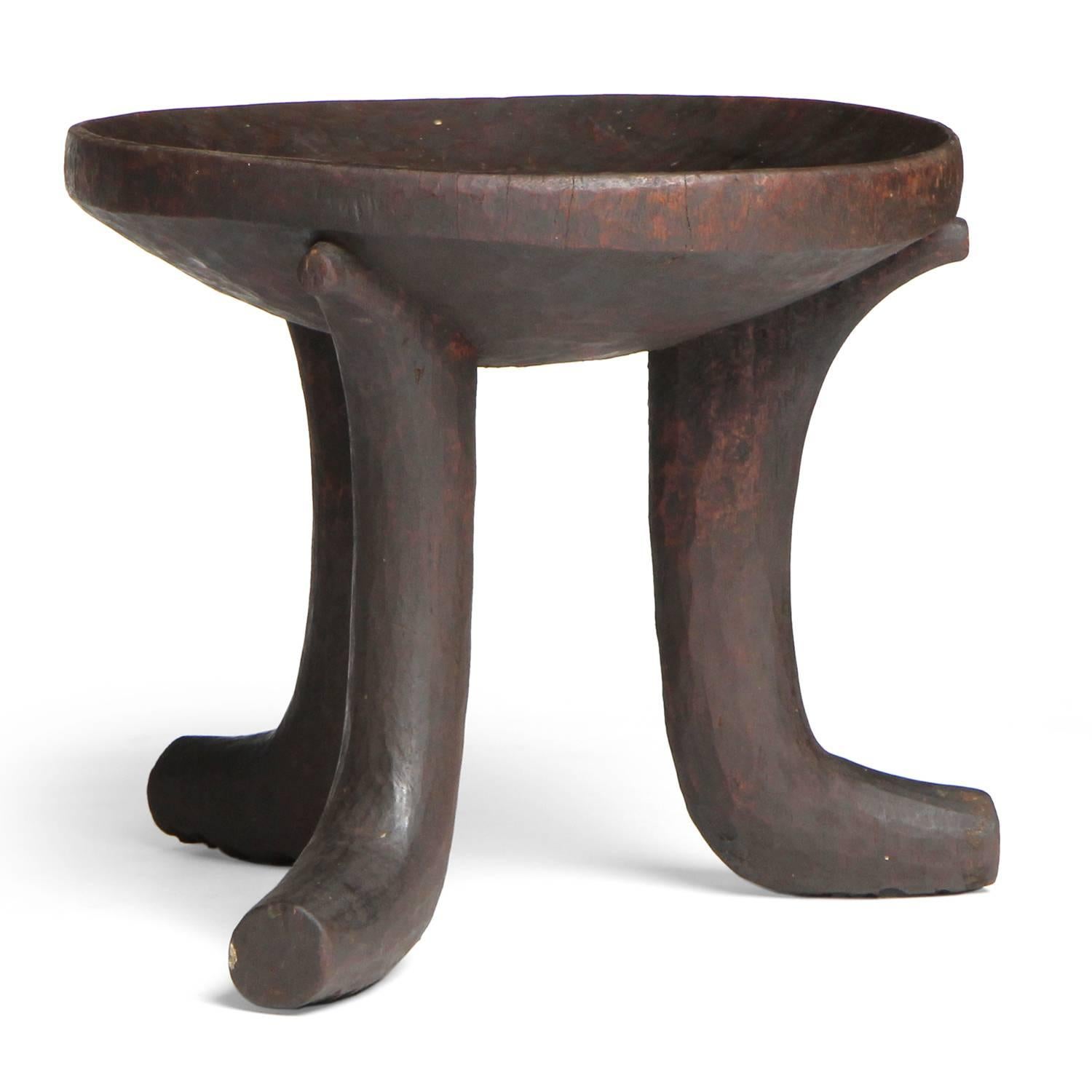 A well carved and warmly patinated tribal stool made from a single block of hardwood and having three splayed legs.